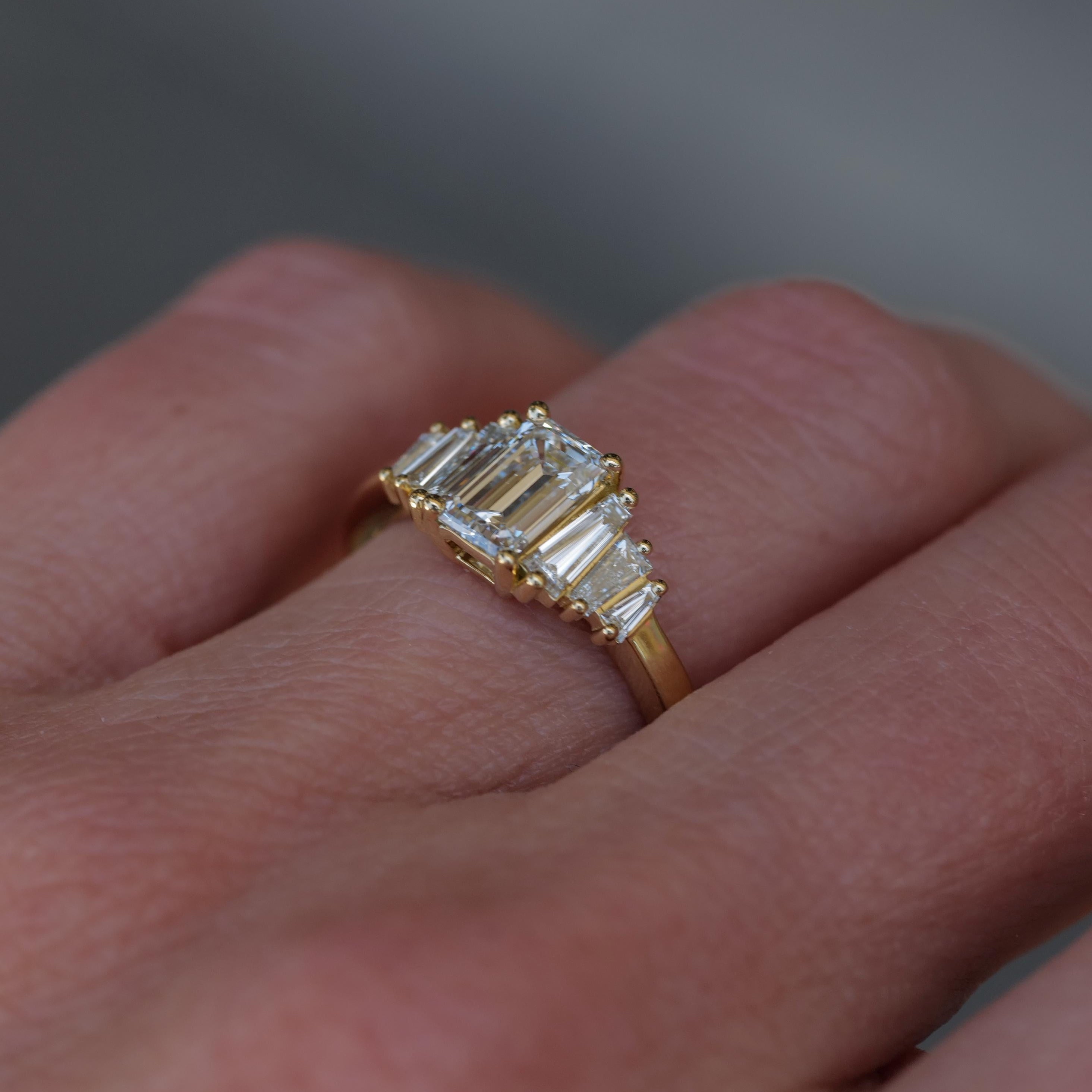 A Fiat Lux Classic Calypso ring with a 1.02ct emerald cut diamond is worn on a finger.