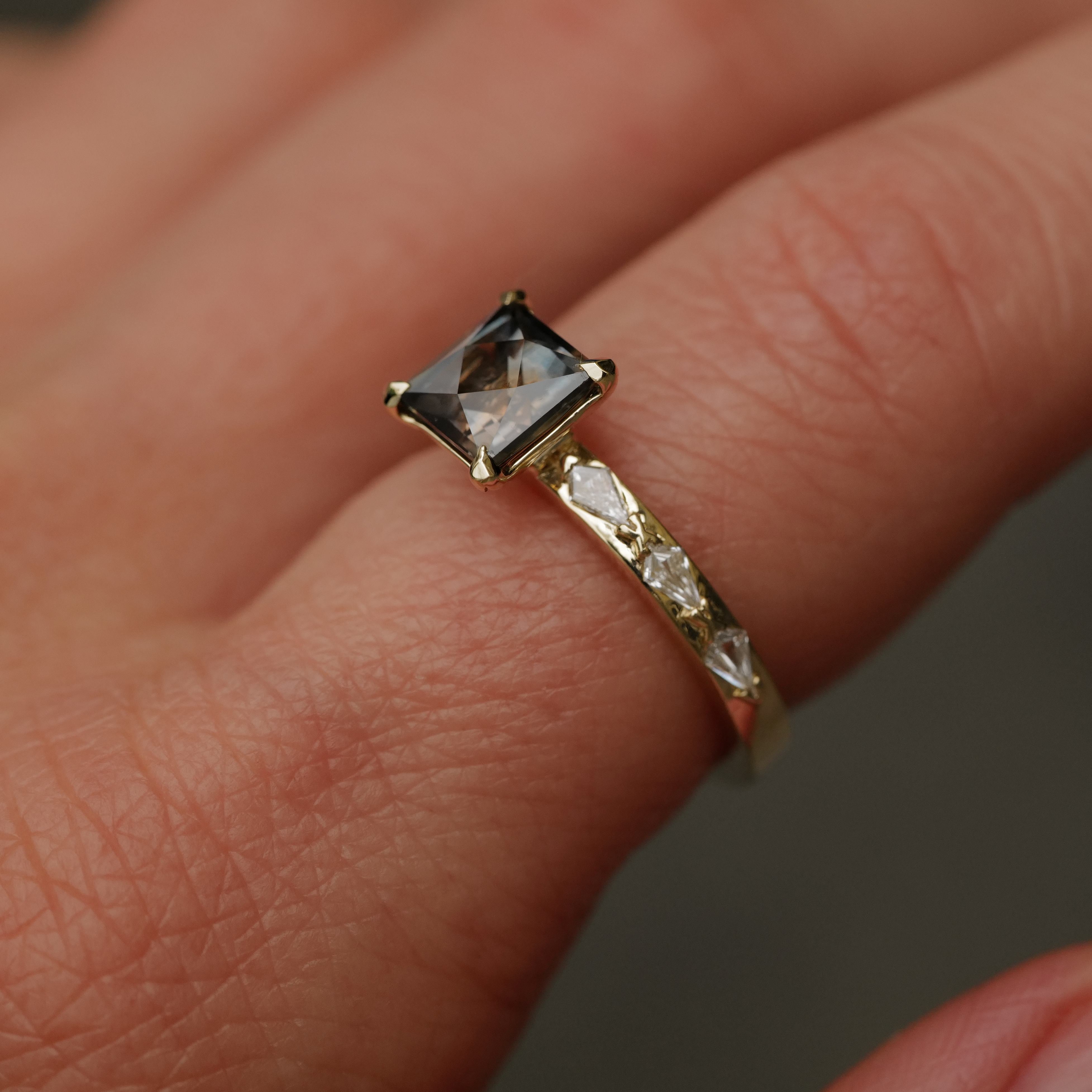 A hand wears Fiat Luxs Classic Theia Ring—1.70ct plum sapphire, 14K gold, with diamond accents on the band.