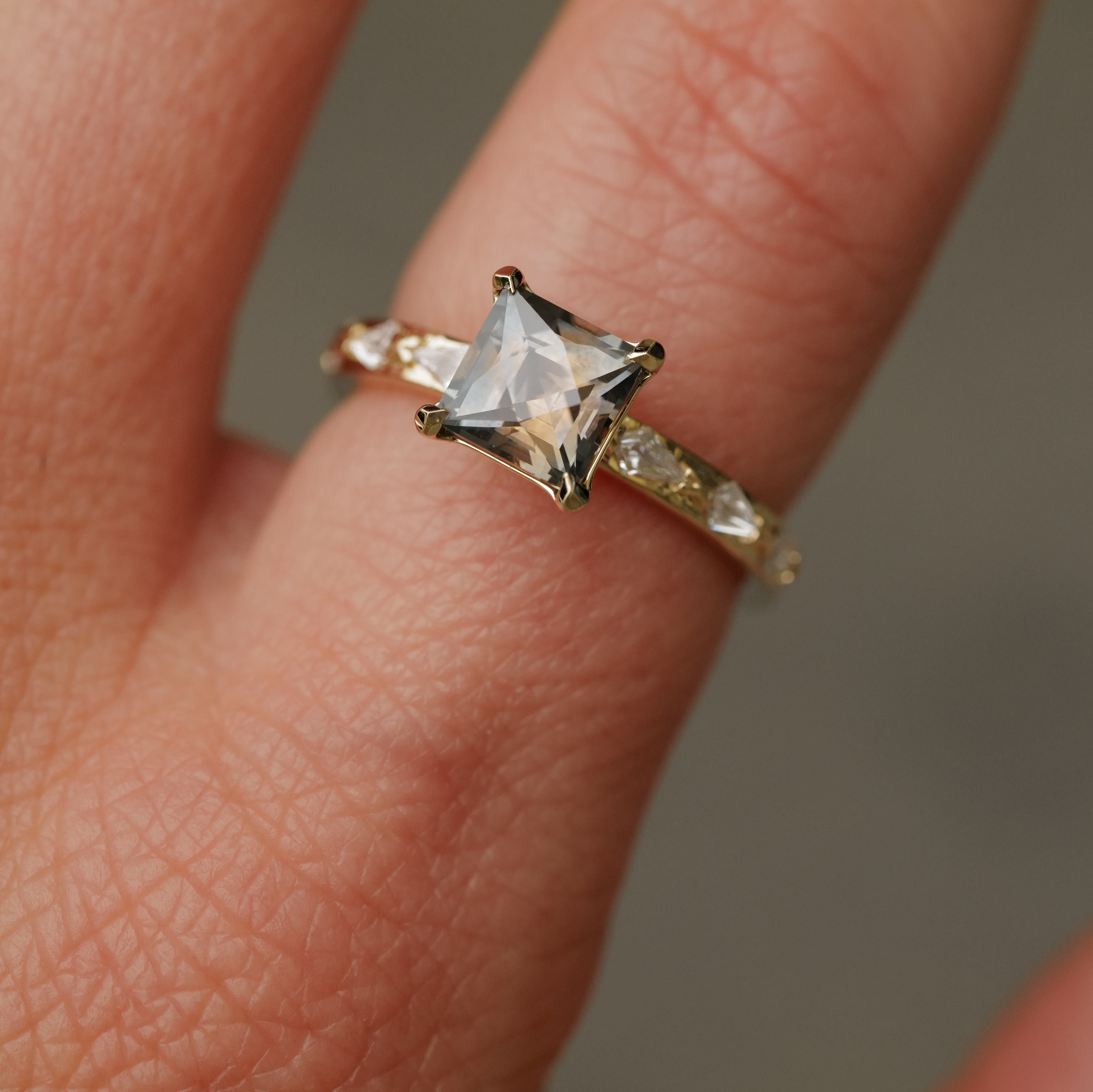 A hand wearing the Fiat Lux Classic Theia Ring with a 1.70ct plum sapphire and sparkling diamond accents.