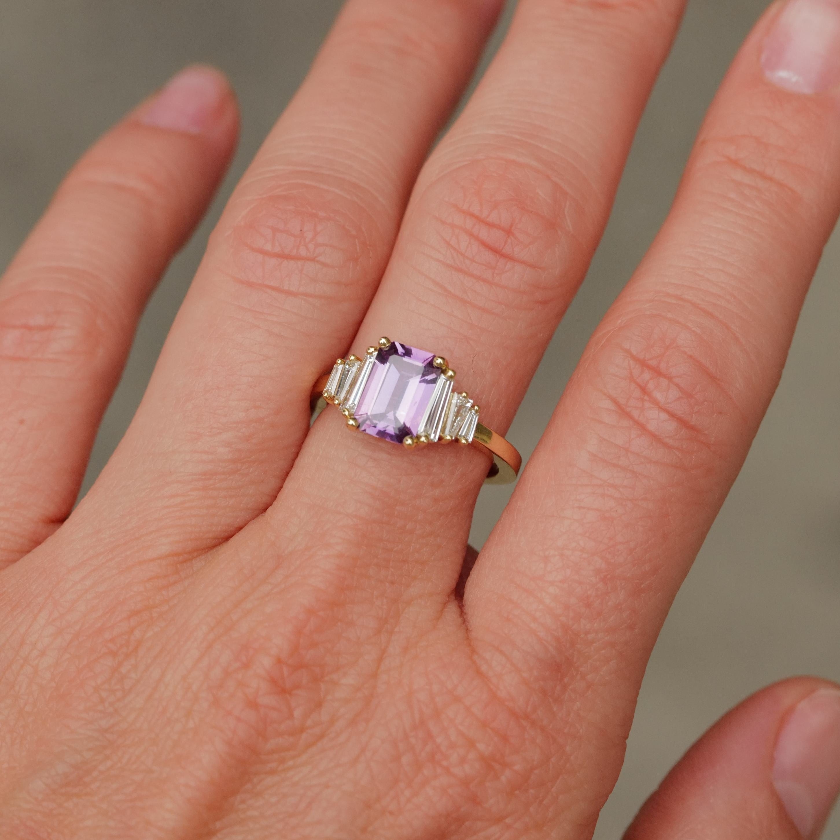 A hand wearing the Fiat Lux Grande Calypso ring with a 1.94ct mulberry pink sapphire and diamond baguettes.