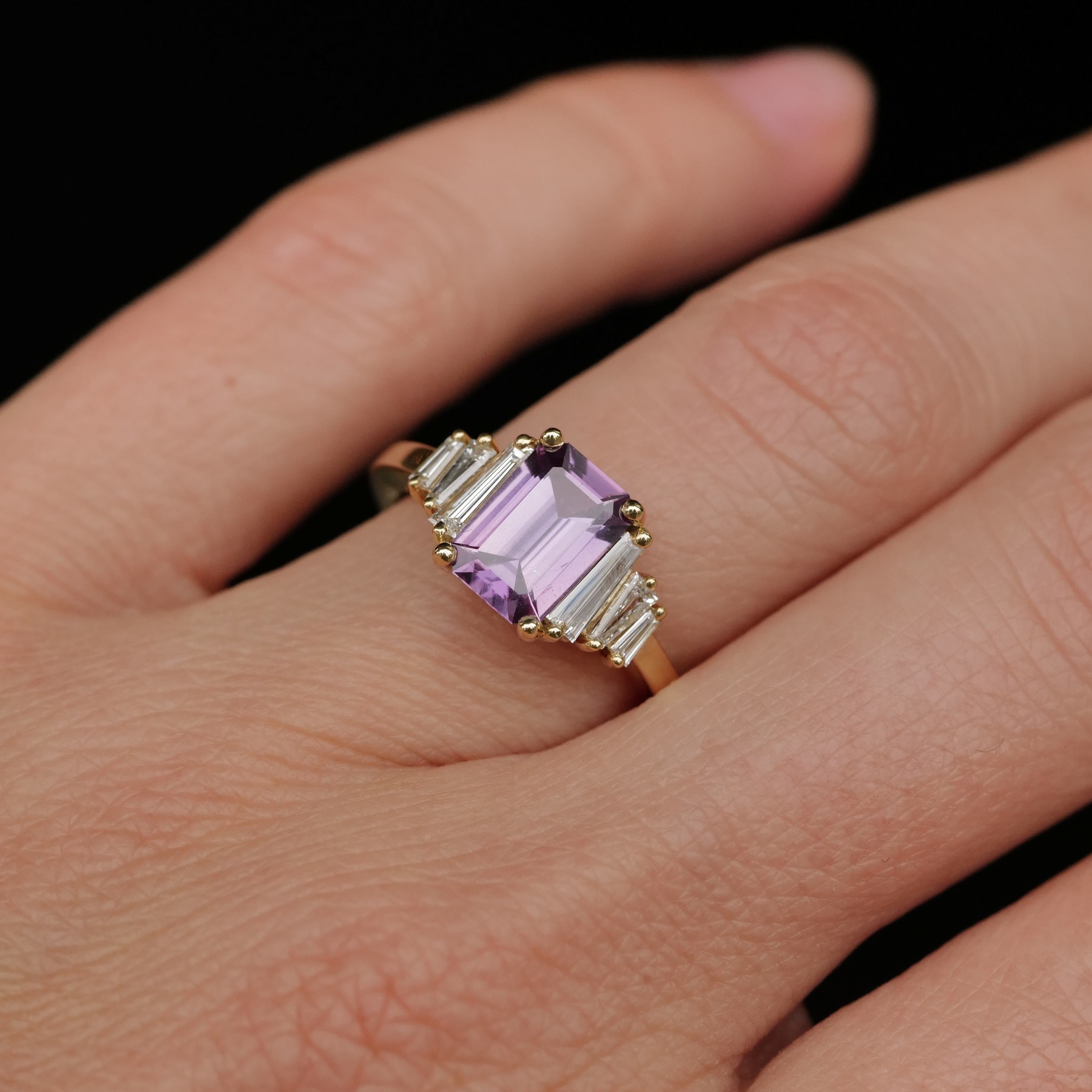 The Grande Calypso Mulberry Pink Sapphire ring by Fiat Lux sparkles with diamonds against a black background.