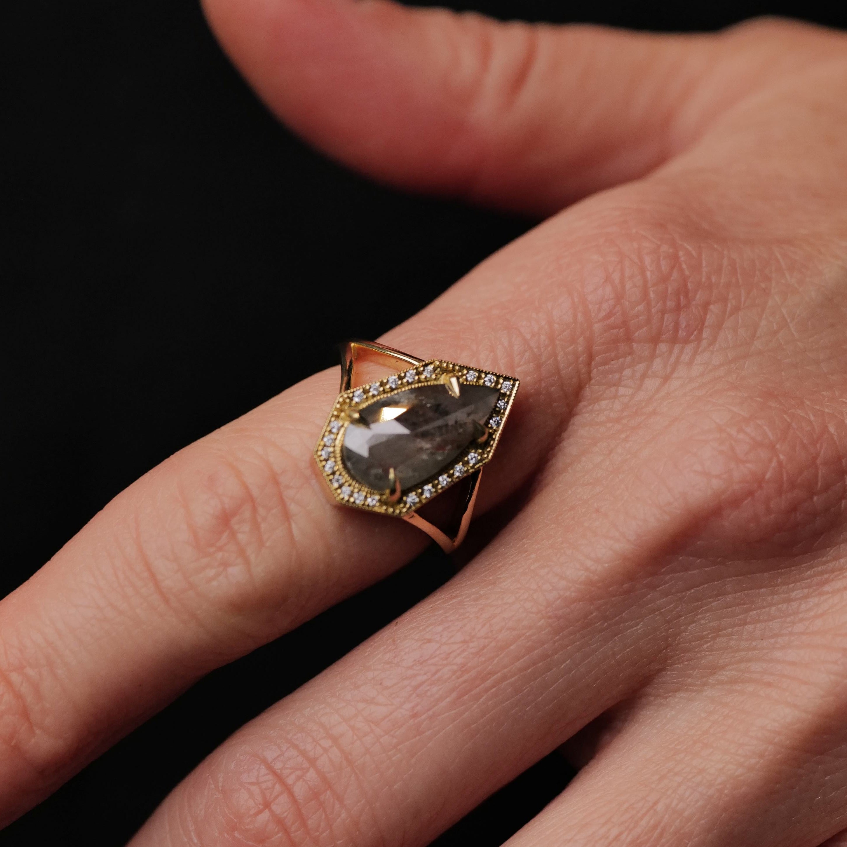 A hand wearing the Fiat Lux Grande Phoebe Ring with a 2.34ct soft grey salt & pepper diamond and small accent diamonds.