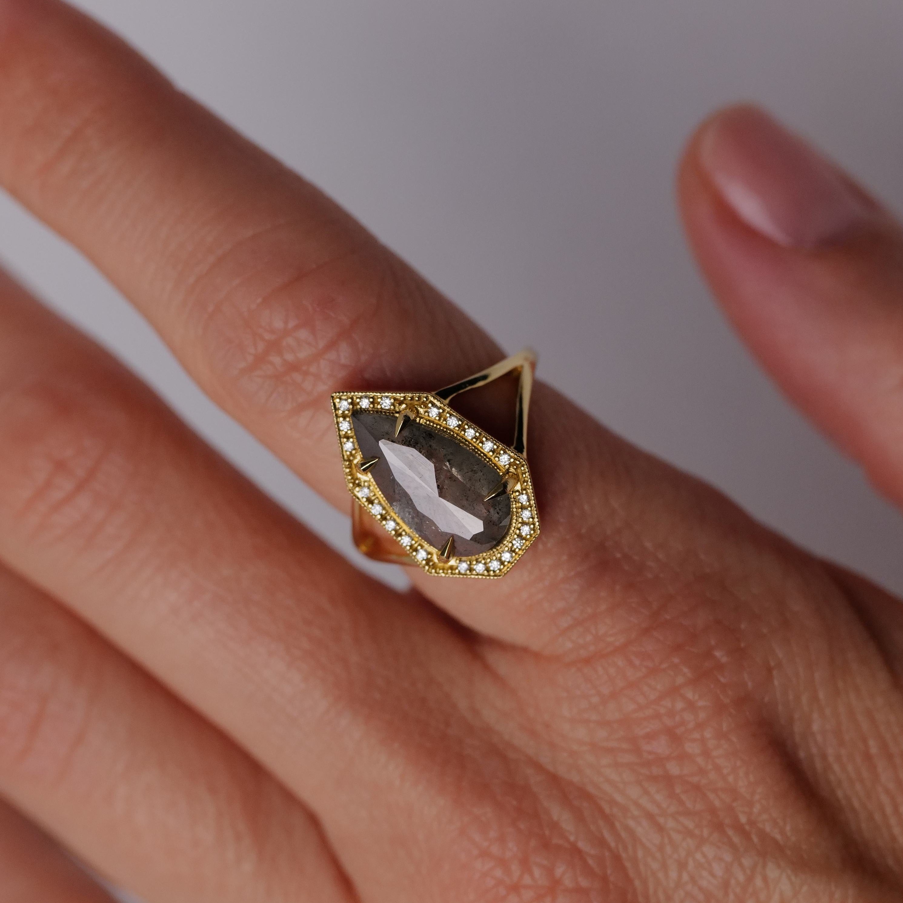 Hand wearing Fiat Luxs Grande Phoebe Ring with a 2.34ct soft grey salt & pepper diamond, ringed by small diamonds.