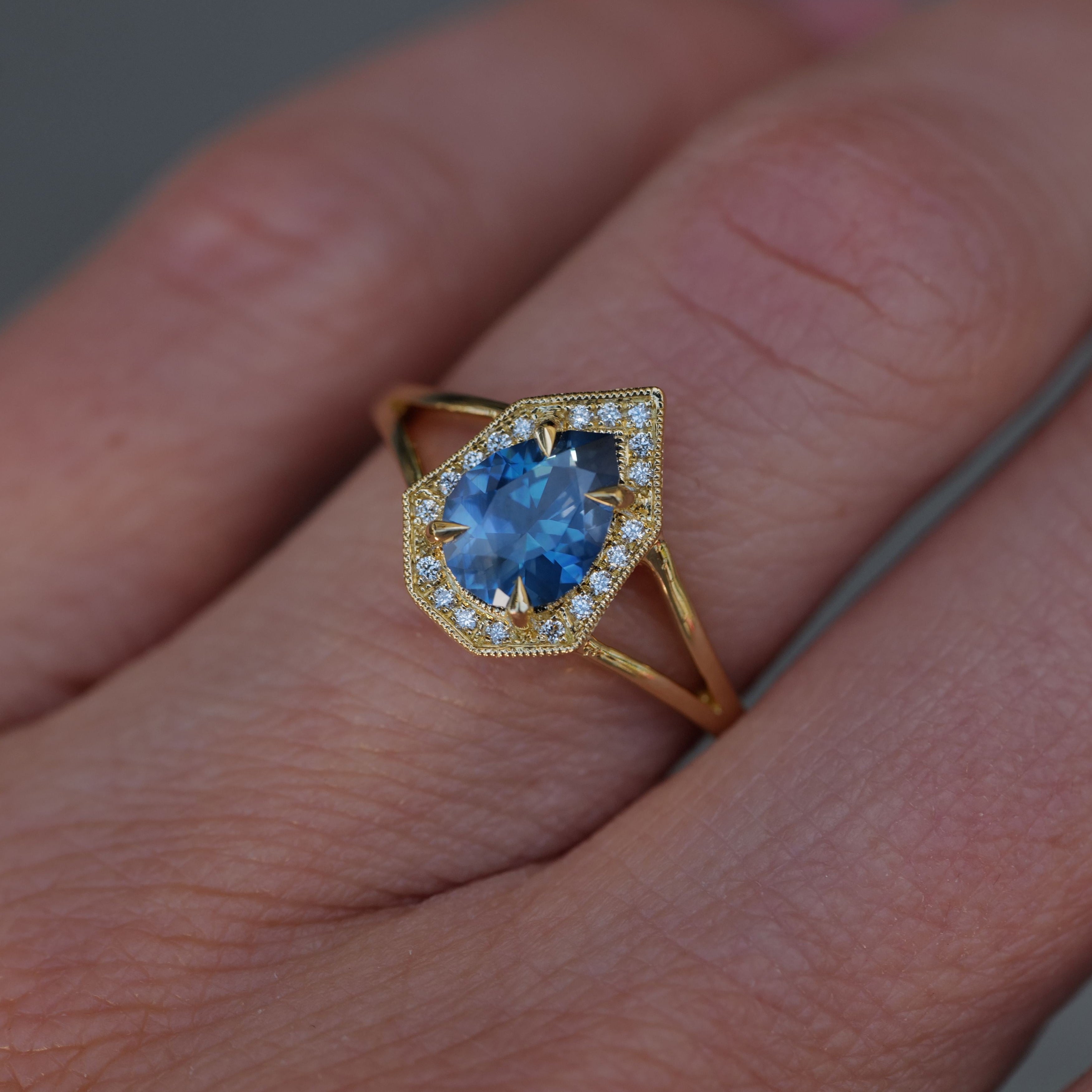 The Fiat Lux Petite Phoebe ring features a 1.15ct denim blue Montana sapphire with a diamond halo in 18K gold.