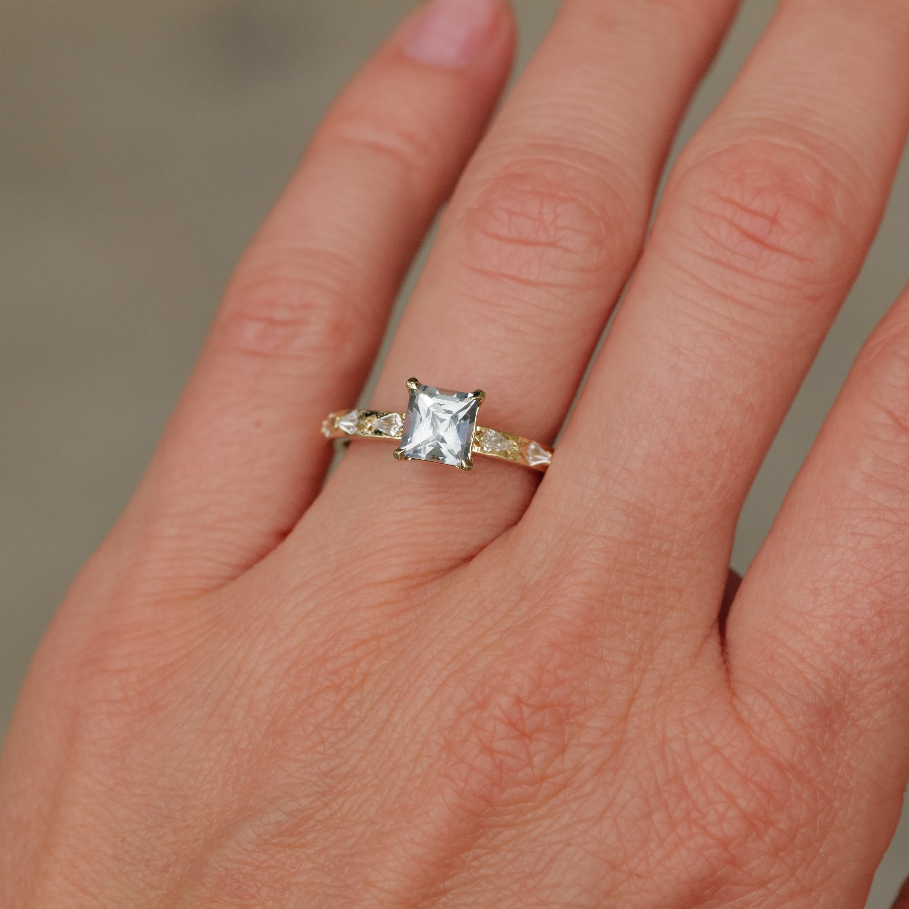 A hand wears the Fiat Lux Classic Theia Ring with a 1.41ct aqua sapphire on the ring finger.