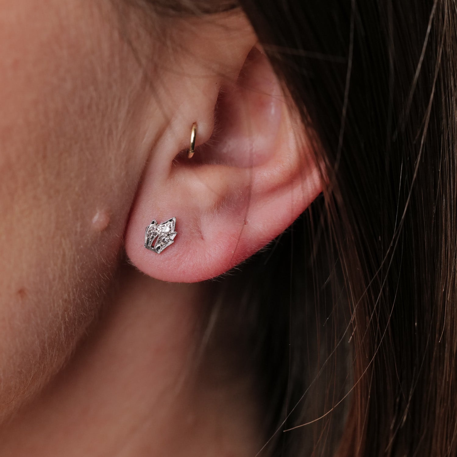 Close-up: an ear adorned with Vintage Platinum Leaf Earring - Diamond by Vintage, featuring intricate platinum details.