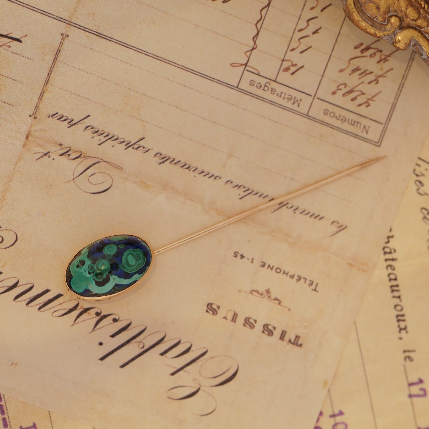 The Vintage Antique Azurmalachite Stick Pin rests on vintage handwritten papers.