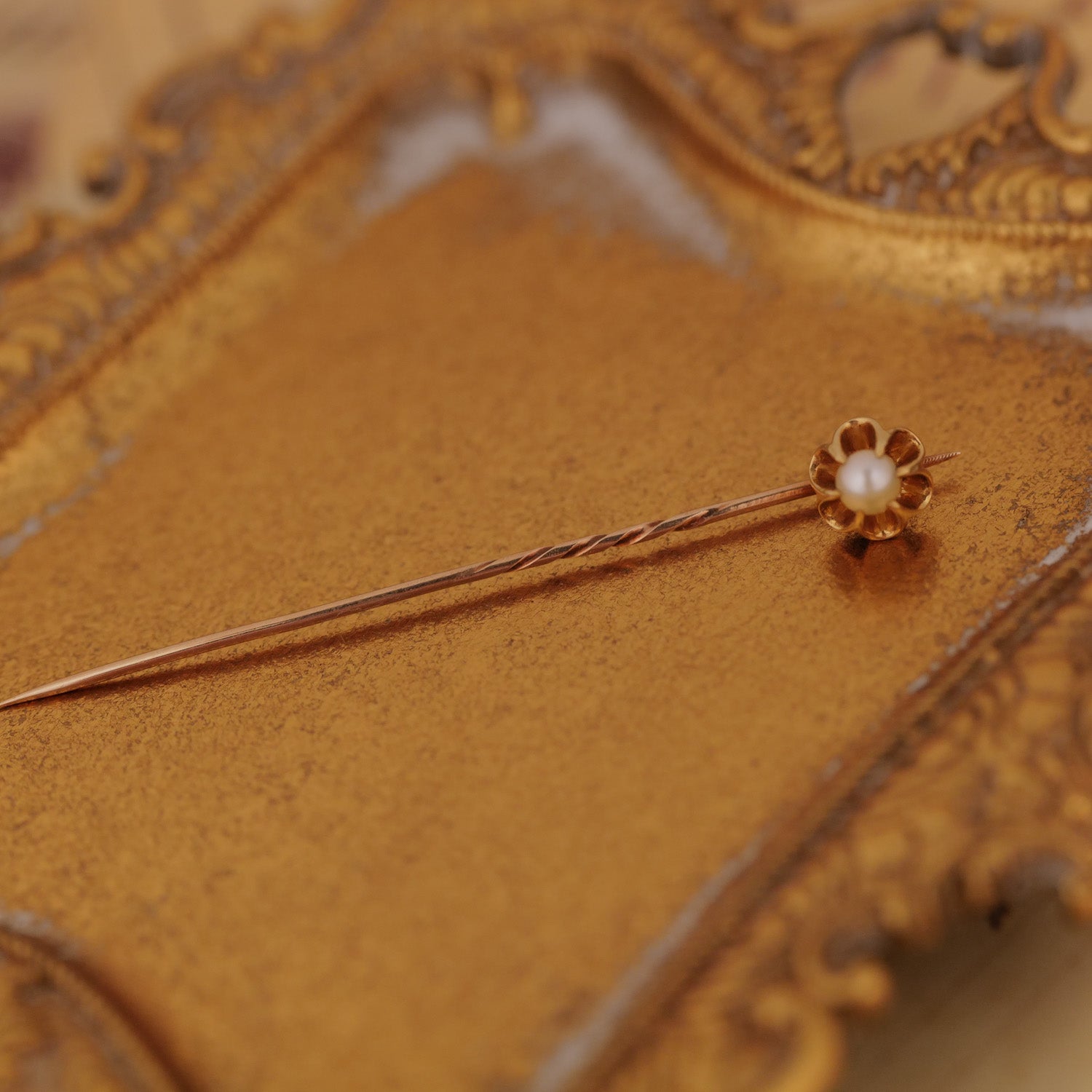 The Vintage Antique Pearl Belcher Stick Pin rests on an ornate gold tray.
