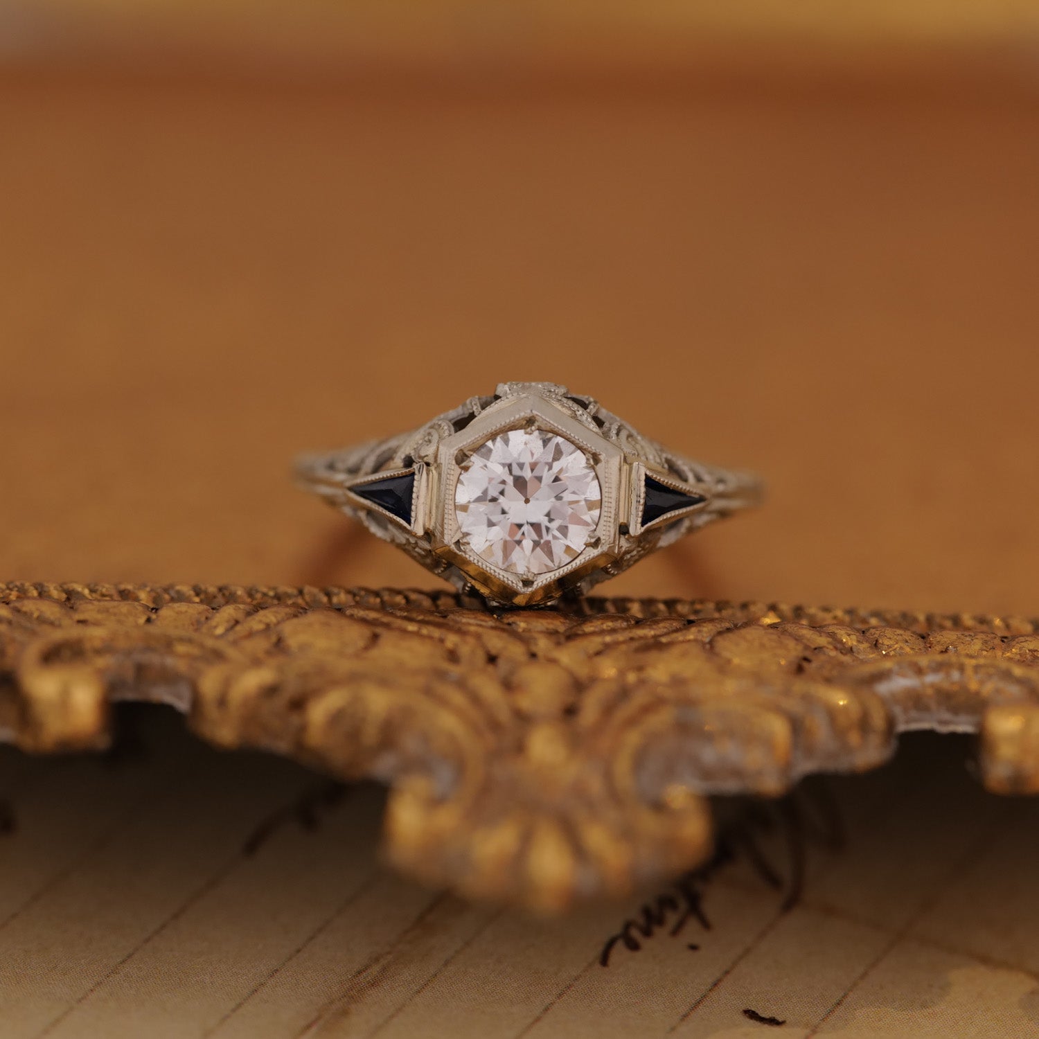 A vintage gem, the Art Deco Botanical Hexagon Ring by Vintage shines atop an ornate, gold-edged surface.