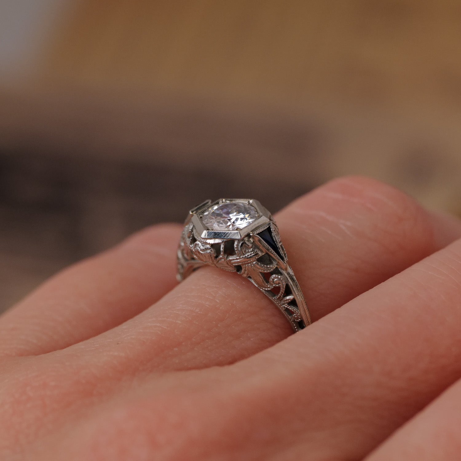 A close-up of a hand wearing the Vintage Art Deco Botanical Hexagon Ring with a clear gemstone in a classic setting.