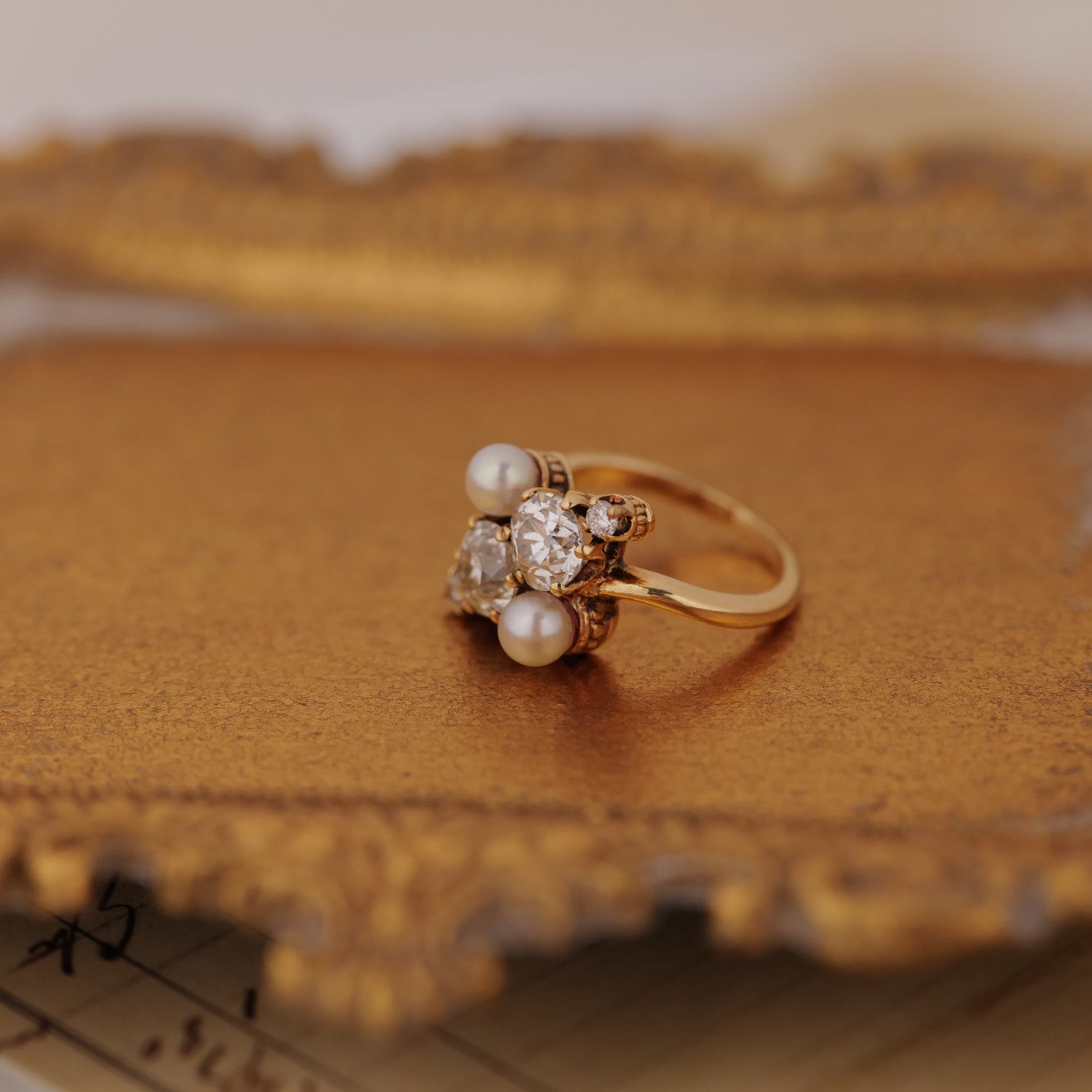 Vintage Double Pearl Diamond Ring by Vintage with antique pearls and old-cut diamonds on an ornate gold tray.
