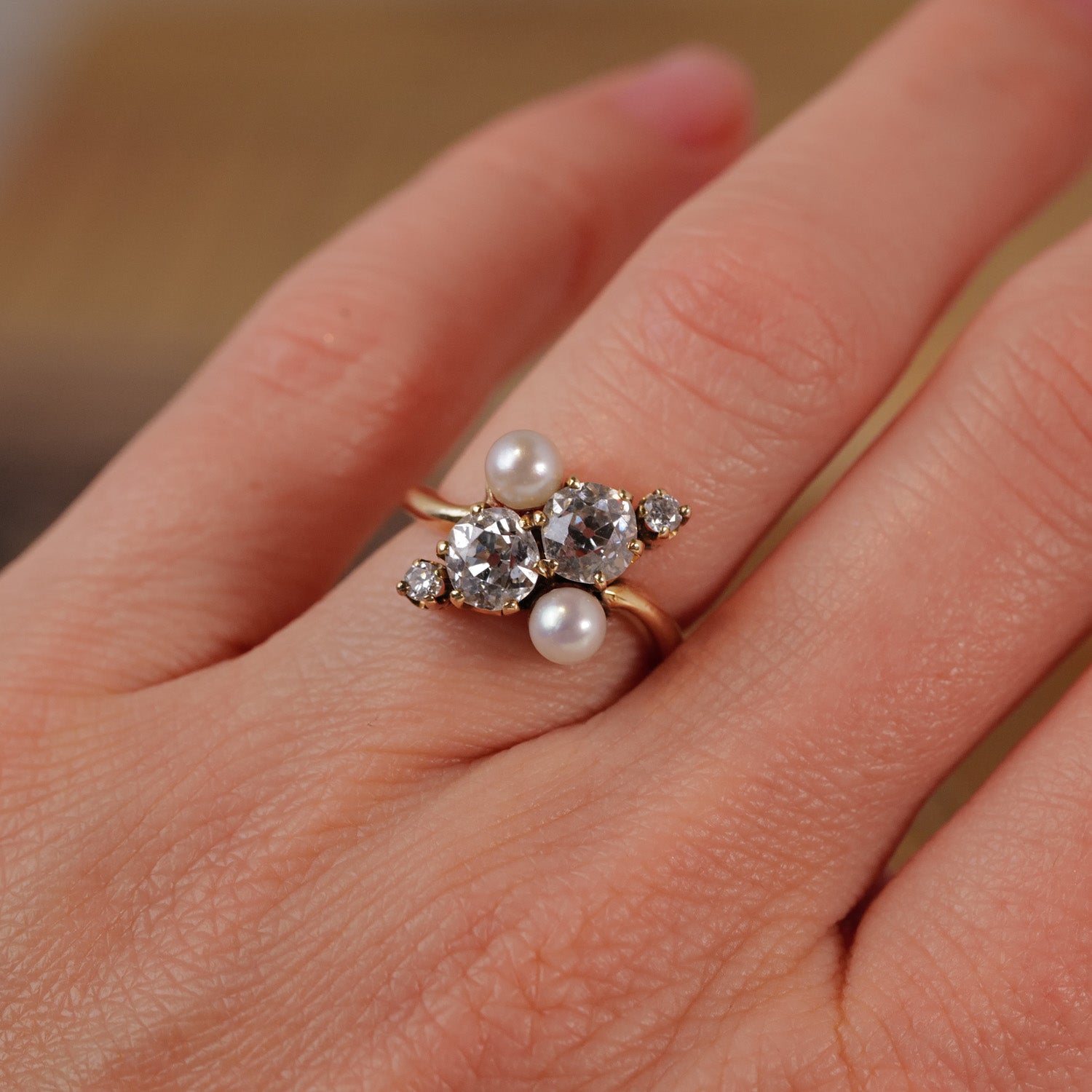A hand wearing Vintages Double Pearl Diamond Ring with an Old European-cut diamond and two antique pearls.