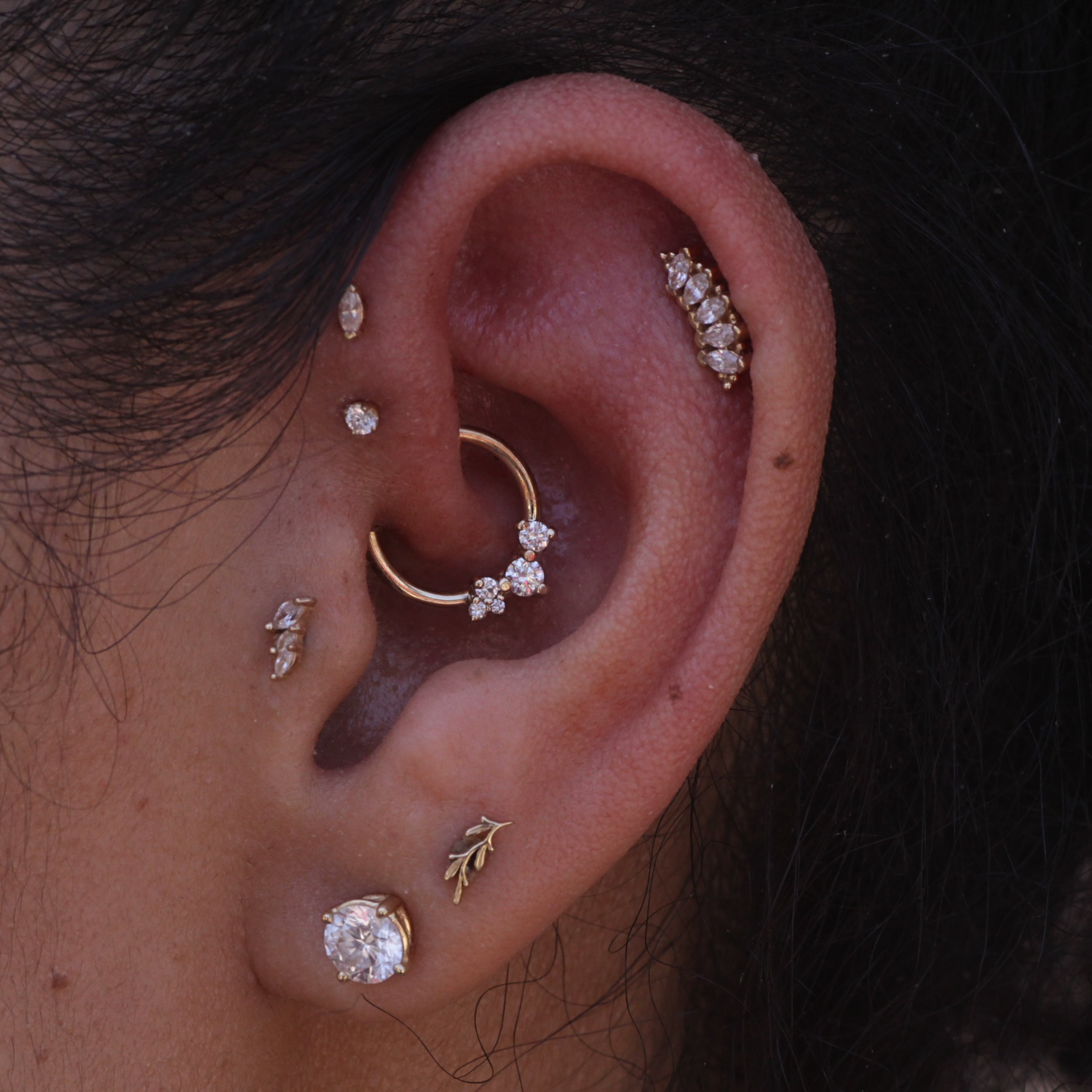 Close-up of an ear adorned with BVLAs 14k gold Ripple Ring piercing jewelry — a stunning, elegant seam ring.