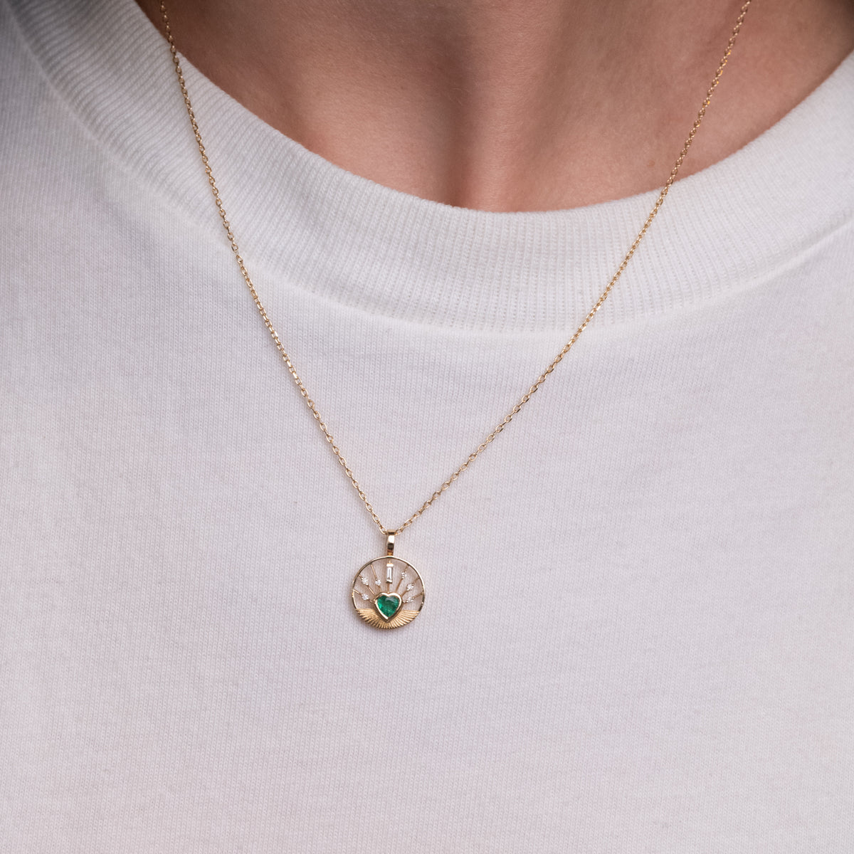 Celine Daoust Heart Medal Necklace - Emerald, a 14K gold sunbeam pendant with a green heart-shaped stone and diamonds.