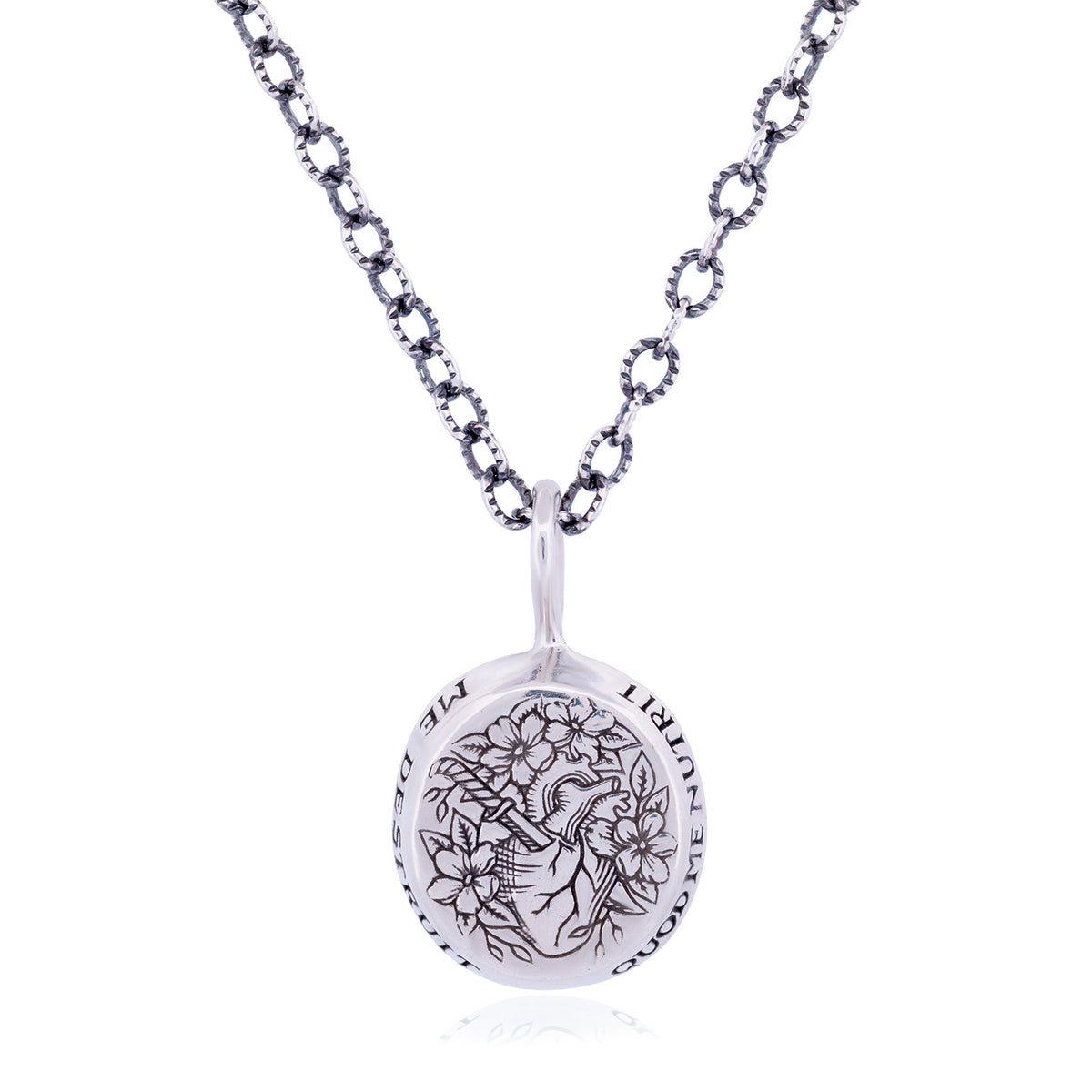 A silver pendant necklace featuring a circular medallion engraved with a floral wreath. The pendant reads 'Quod Me Nutrit Me Destruit' which translates to 'That Which Nourishes Me Also Destroys Me'.