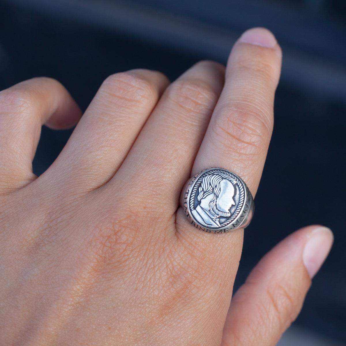 A hand wears Digby & Iona’s Honest Abe Signet Ring, a sterling silver piece engraved with a profile like a wax seal.