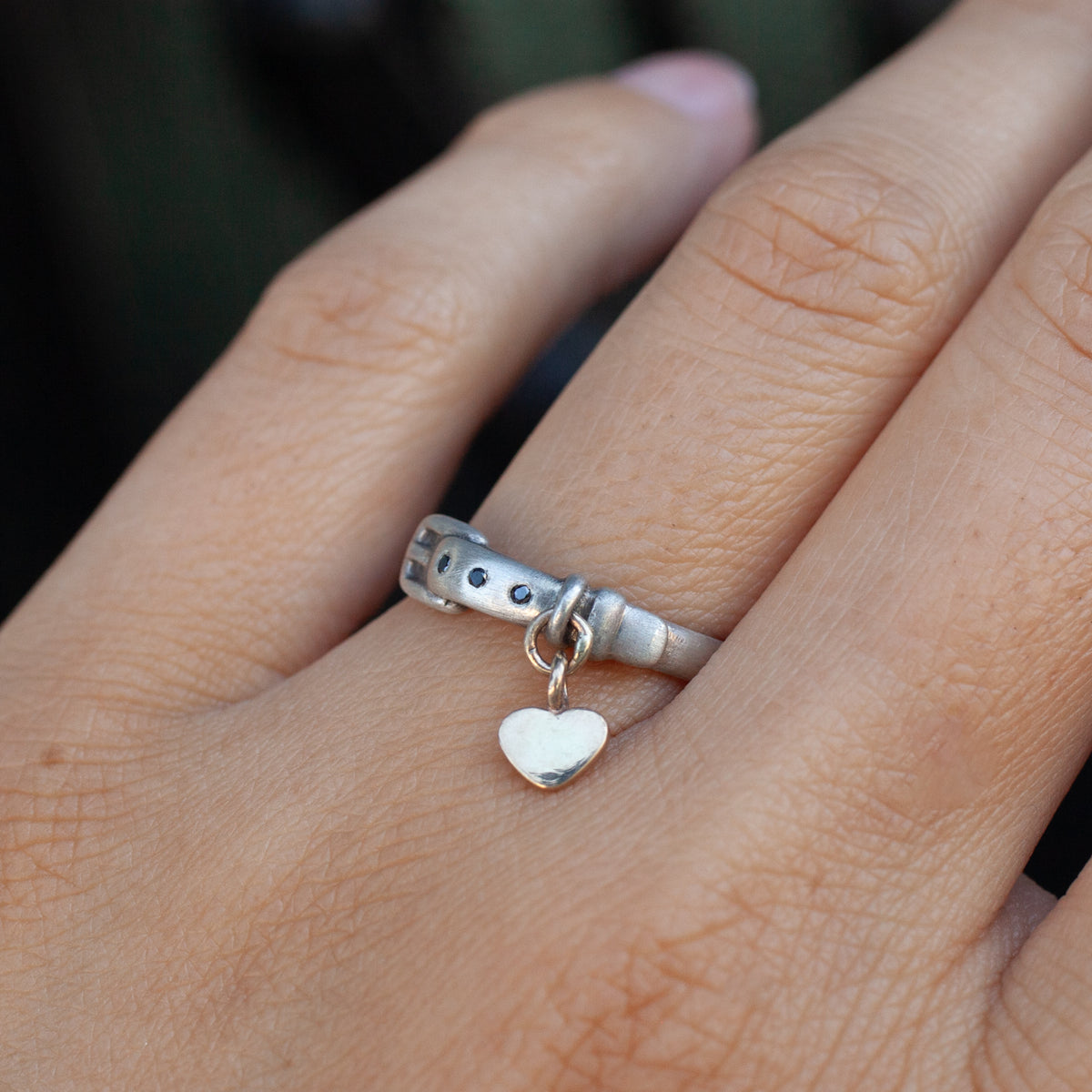 Little Love Pet Collar Ring - Black Diamond, a sterling silver ring designed as a buckled belt with a dangling heart charm.
