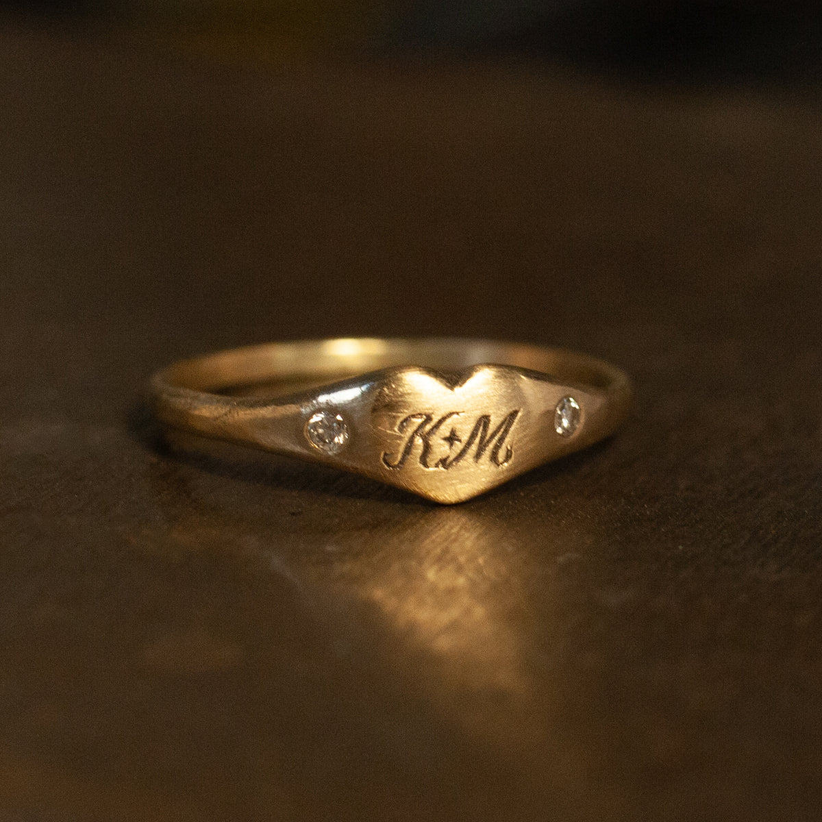 Daisy San Luis Littlest Heart Pinky Ring in 14k gold, custom engraved K+M with two small inset stones.