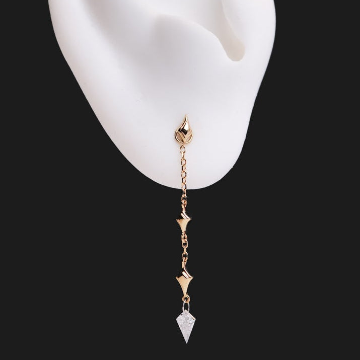 The Fiat Lux North Star Kite Dangle, a 14K gold geometric earring, hangs from a white ear model on black.
