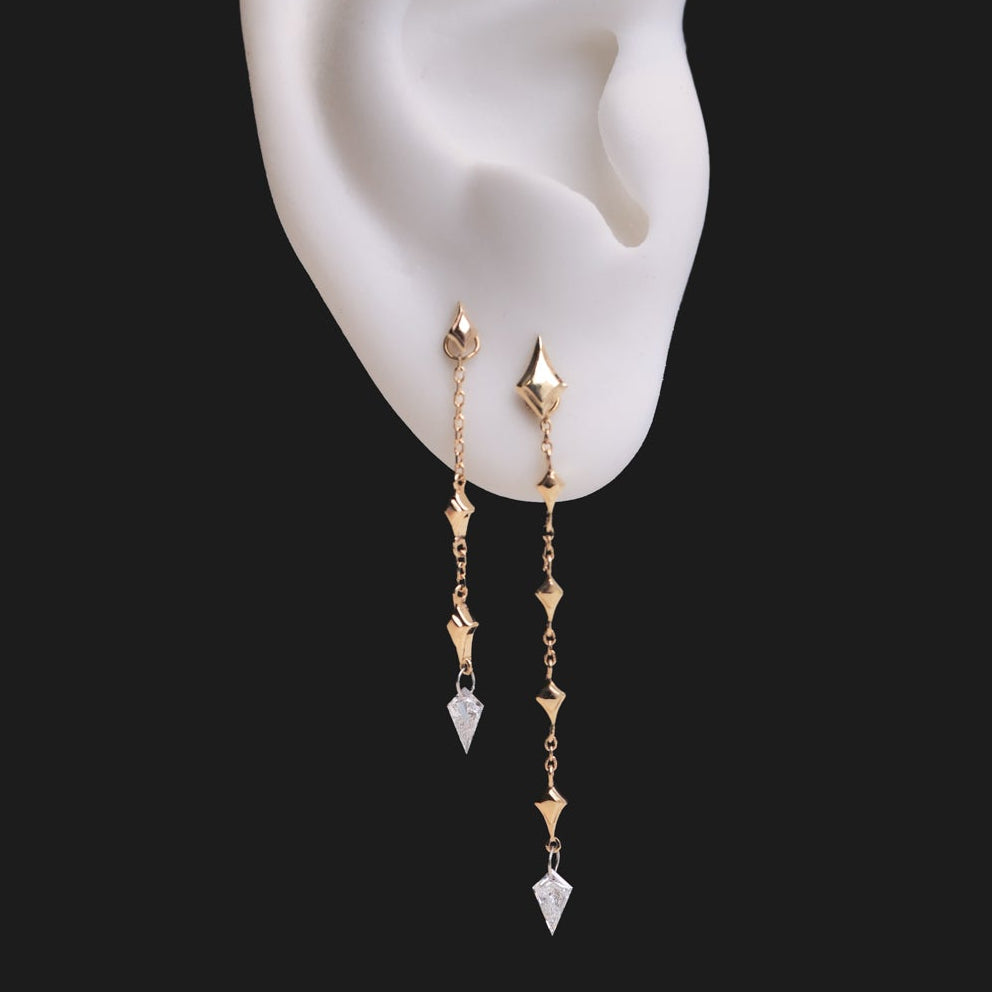 Fiat Lux North Star Kite Dangle earrings: two 14K gold chains with diamond kite charms on a white ear form.