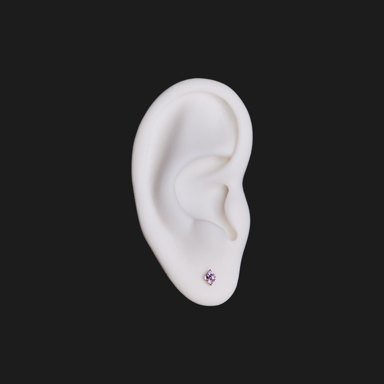 A white model ear wears Fiat Lux’s Grande Sirius Stud - Colored (1.5mm) in gold, shown on a black background.
