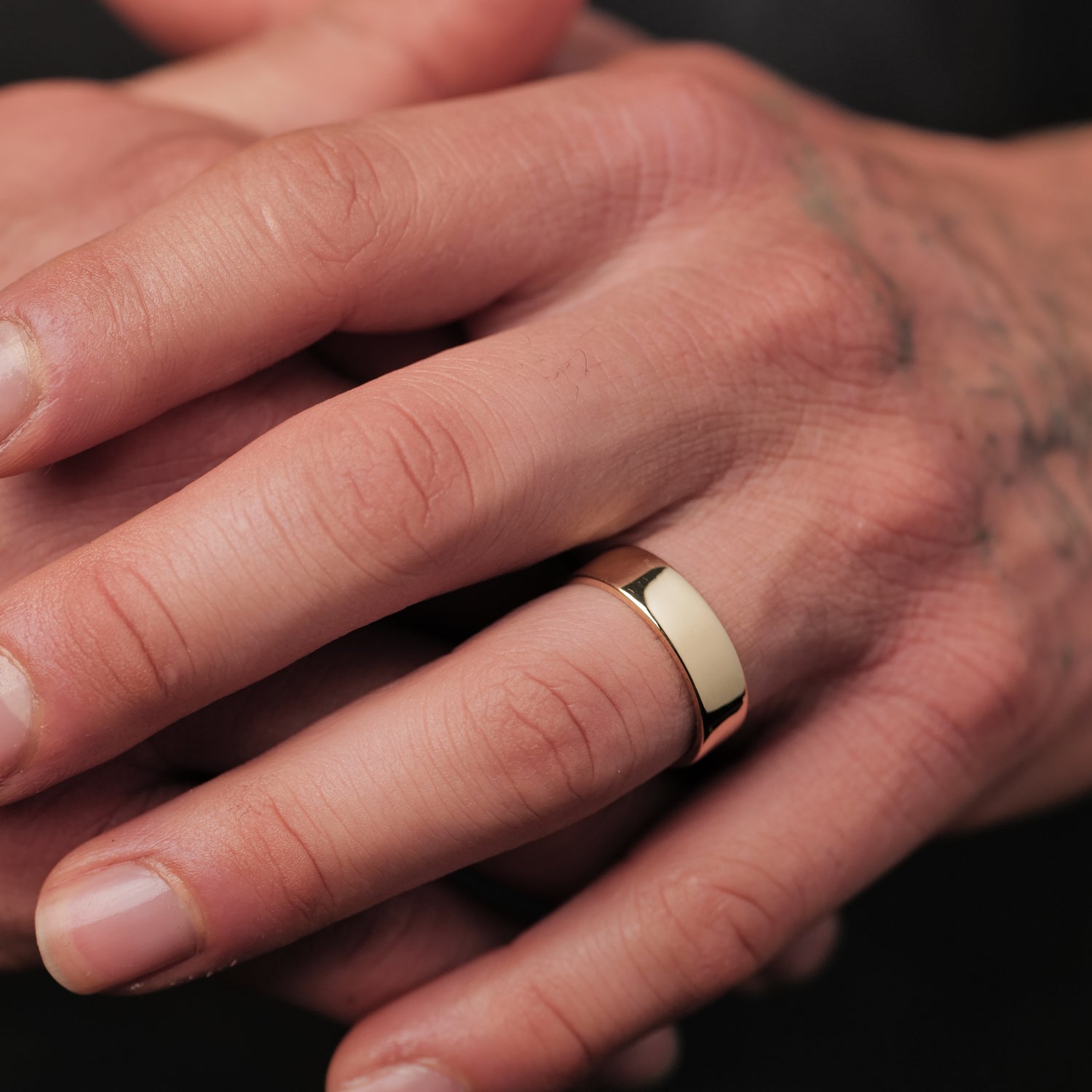 A person wears the Fiat Lux Classic Flat Band (6mm), with tattoos and short, clean fingernails visible.