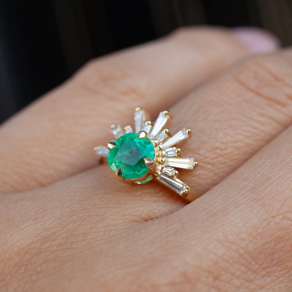 Fiat Lux Grande Demi Feu - Emerald Cushion ring with a cushion-cut emerald and sunburst baguette diamonds on a finger.
