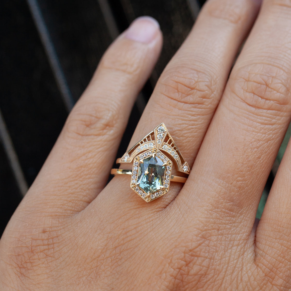 A Grande Hex Hester - Tanzanian Sapphire ring with a matching diamond-accented 18K yellow gold crown band on a finger.