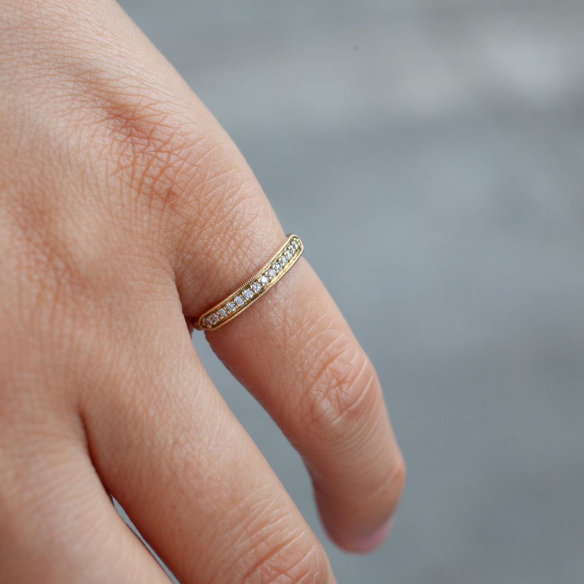 The Tuile Pavé Ring - Diamond by Fiat Lux is shown on a finger with a blurred grey background.