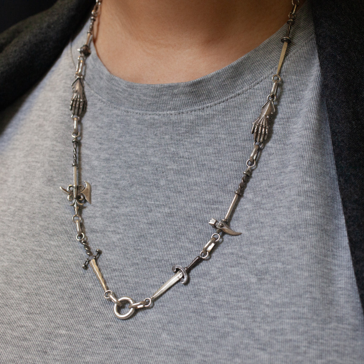 Morgaine Faye Armory Chain necklace in sterling silver featuring repeating charms of hands, swords, and axes.