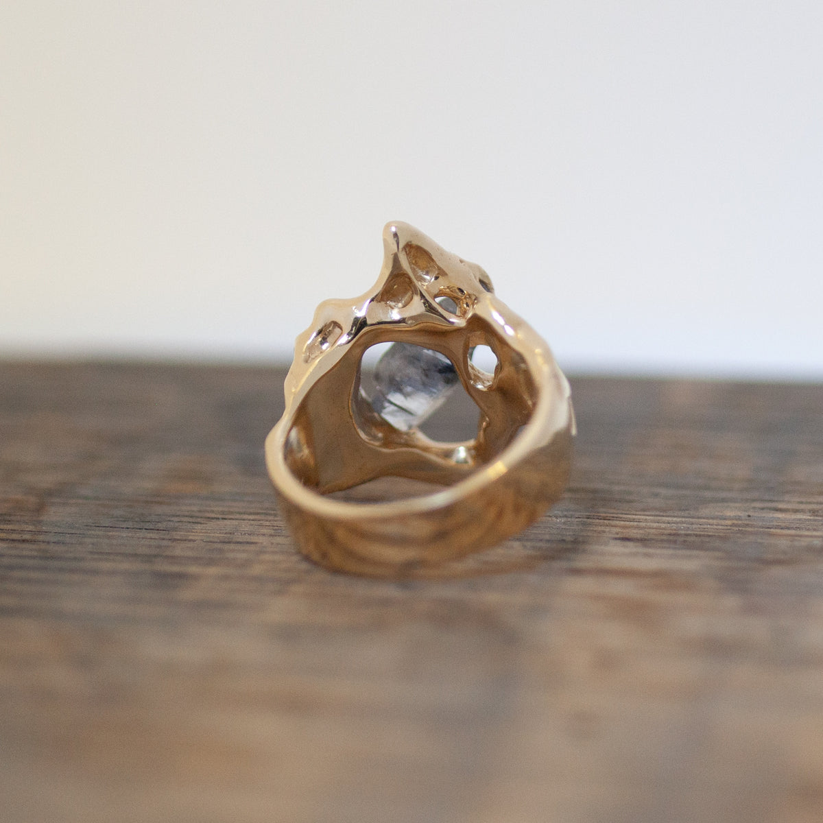 The Yvonne Ring - Sapphire by Nadia Faisal, in 10k yellow gold, features a jagged, organic design on wood.
