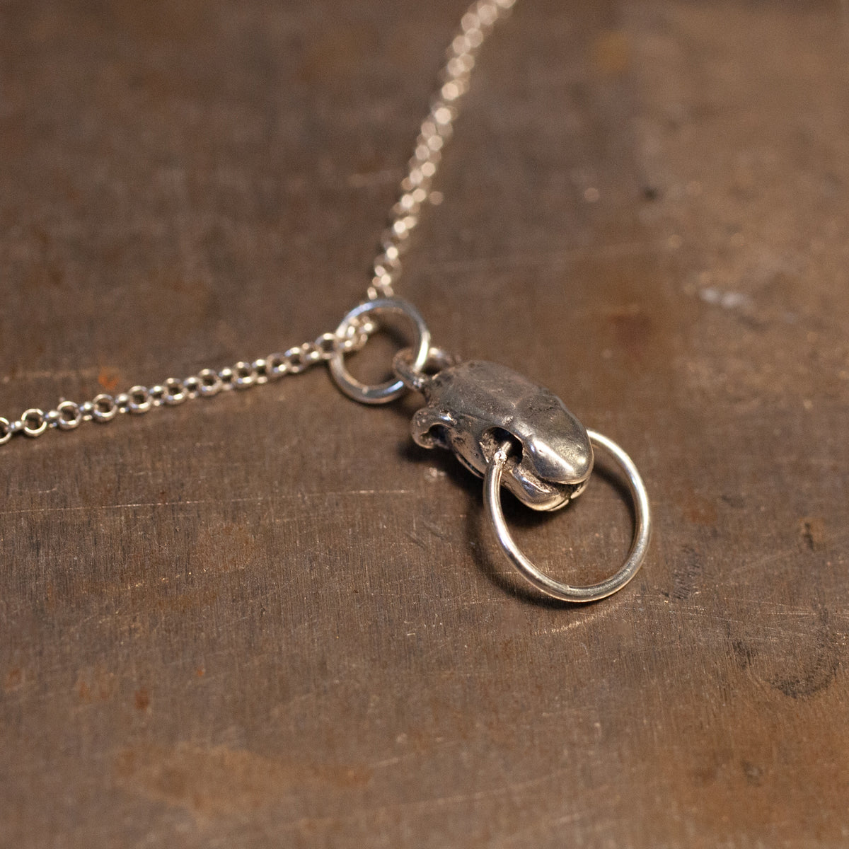 Sacred Order Potentia Door Knocker Necklace: dainty silver chain with a ring pendant hanging from a shaped metal piece.