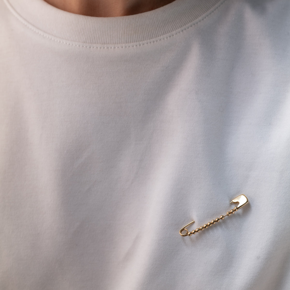 A Vintage Beaded Safety Pin brooch with small metal beads pinned to a white shirt.