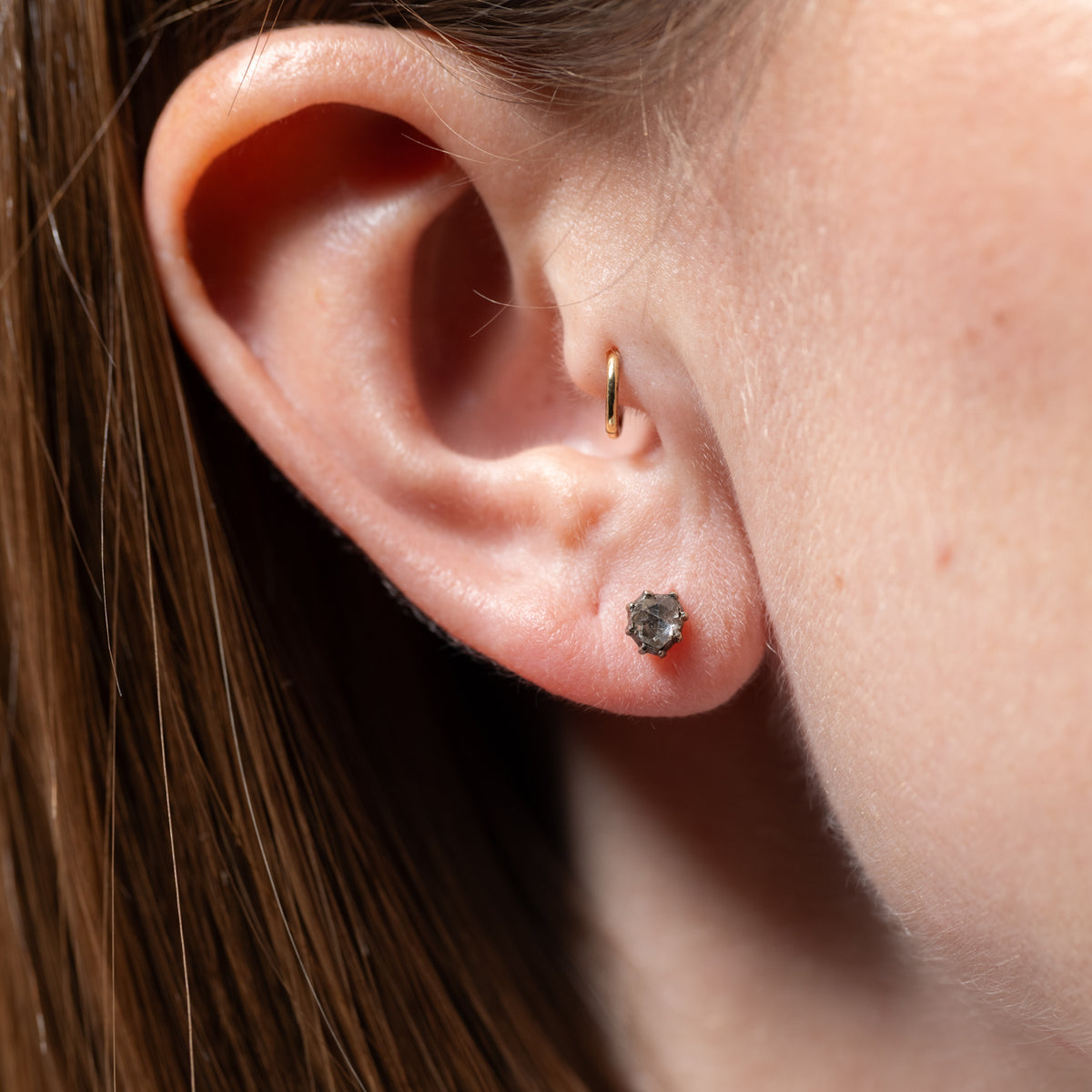 A person’s ear with a small gold hoop in the rook and a Vintage Victorian Rose Cut Single Earring stud in the lobe.