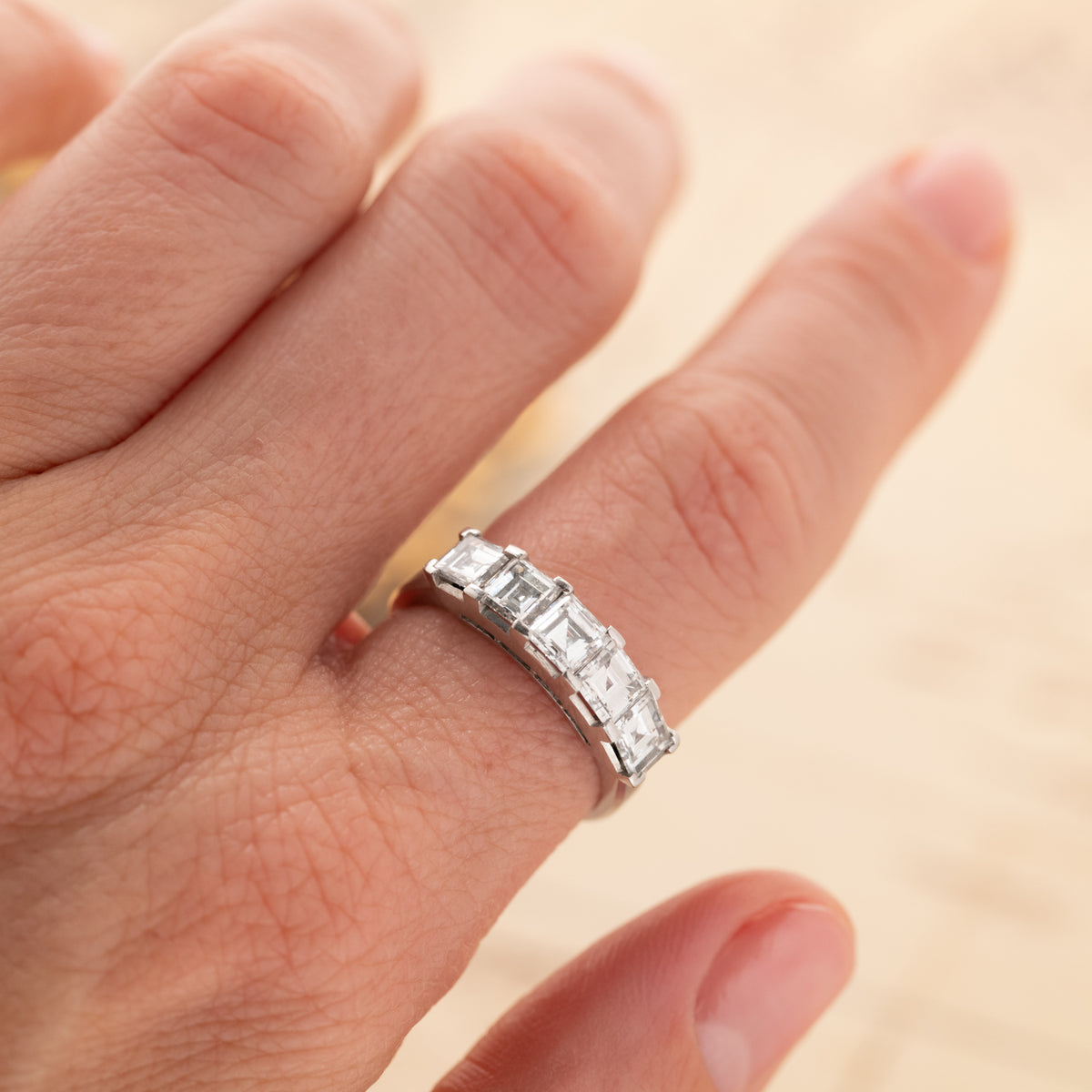 A hand wearing a Vintage Carré Cut Diamond Band (2.04ct) - 5mm featuring five square-cut platinum diamonds.