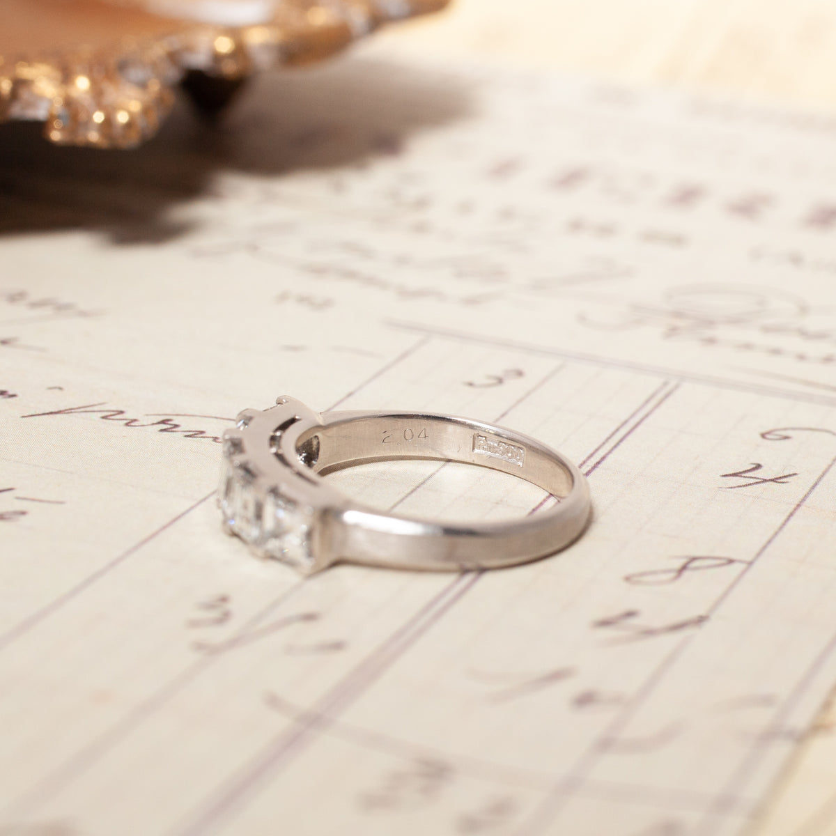 A platinum Vintage Carré Cut Diamond Band (2.04ct) - 5mm with five square-cut diamonds resting on a handwritten document.