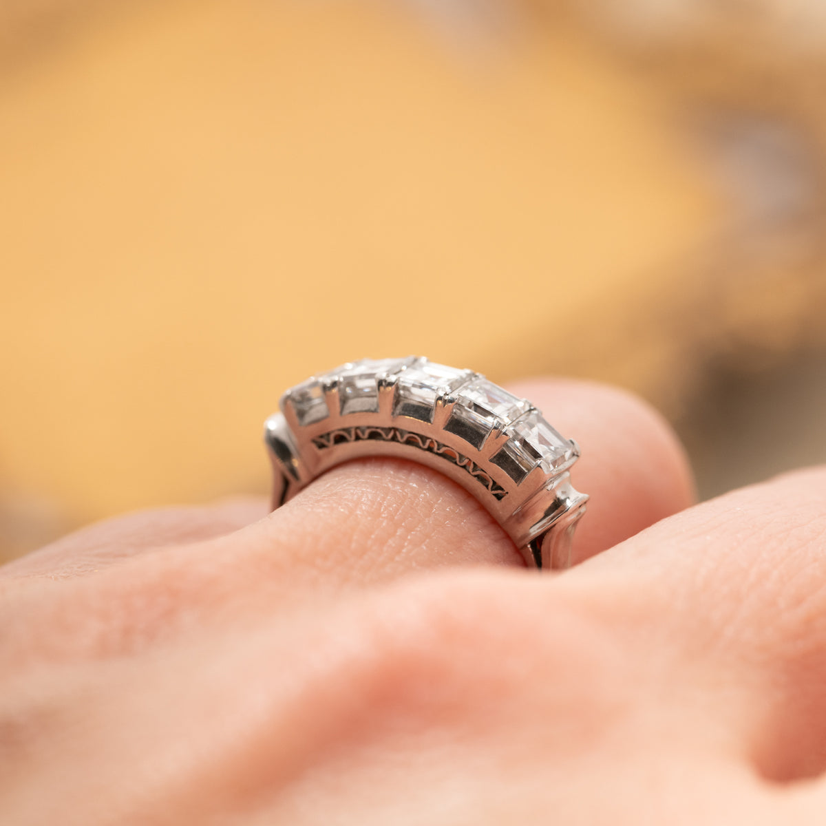 A Vintage Carré Cut Diamond Band - 4.5mm with five diamonds set in platinum on a finger.