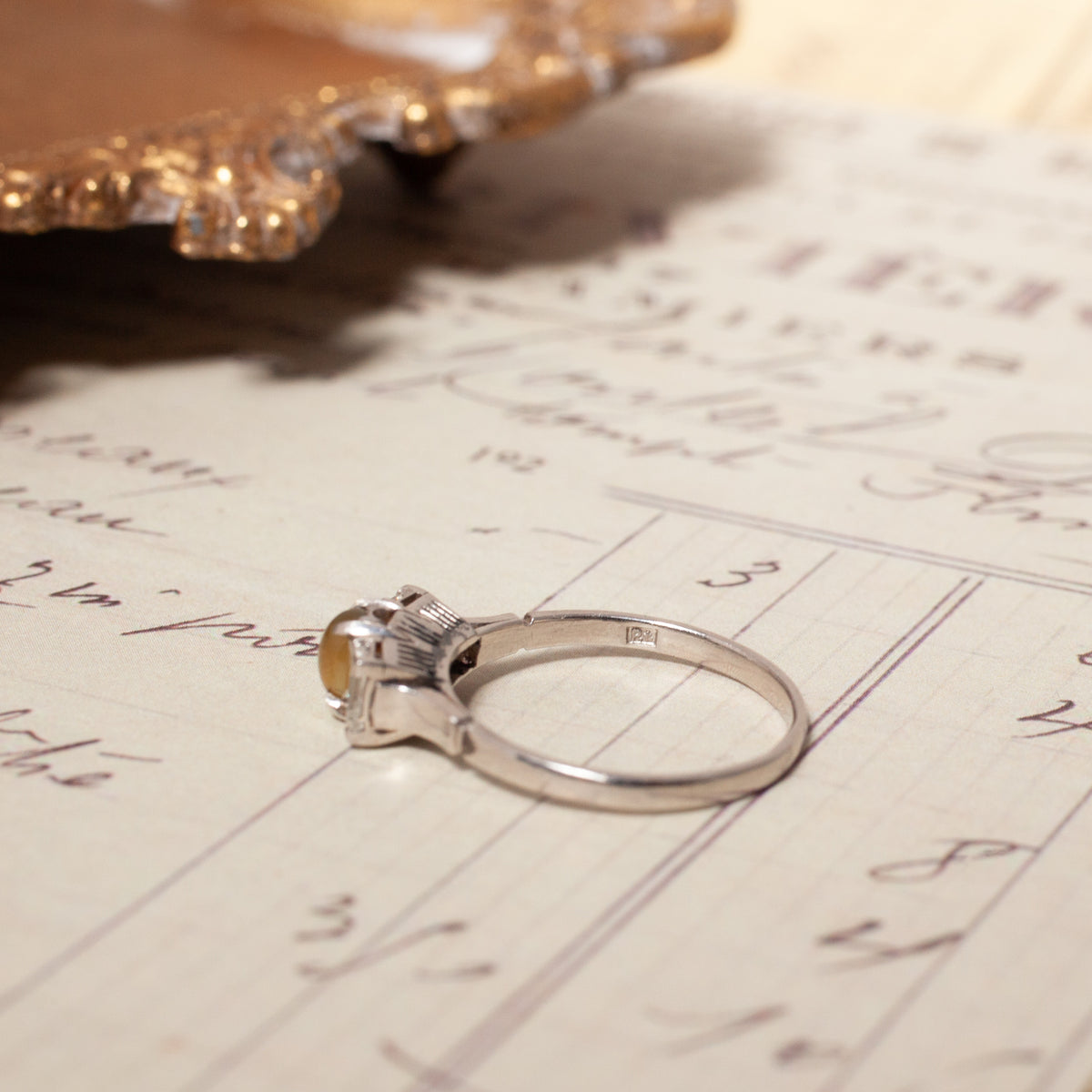Vintage Cat’s Eye Chrysoberyl & Diamond Ring with a chrysoberyl cabochon and baguette diamonds on a handwritten document.
