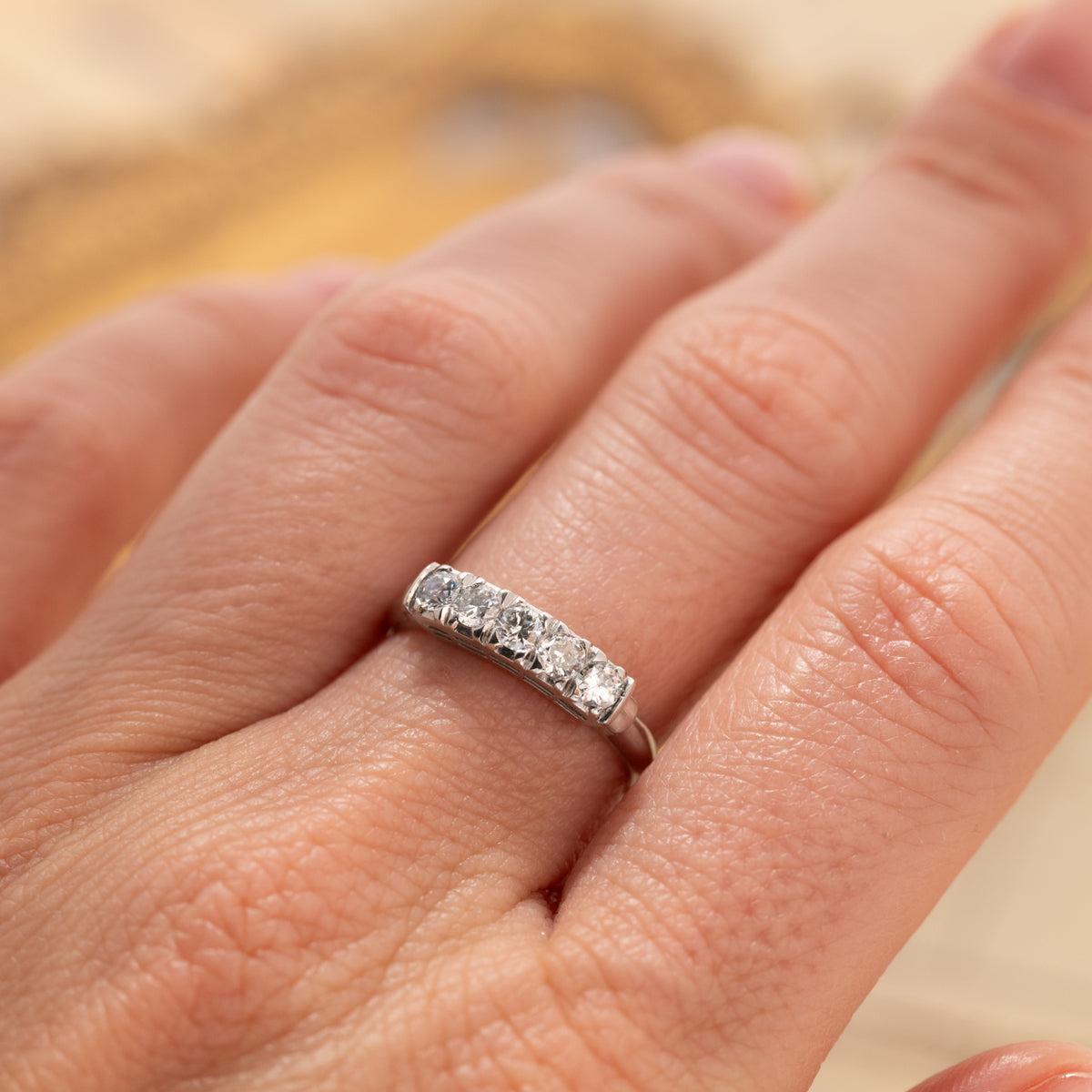 A Vintage Diamond Band Ring in platinum featuring five old euro cut diamonds on a finger.