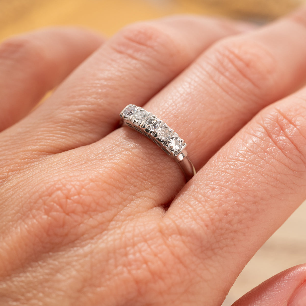 A silver-toned Vintage Diamond Band Ring set with five round diamonds on a finger.