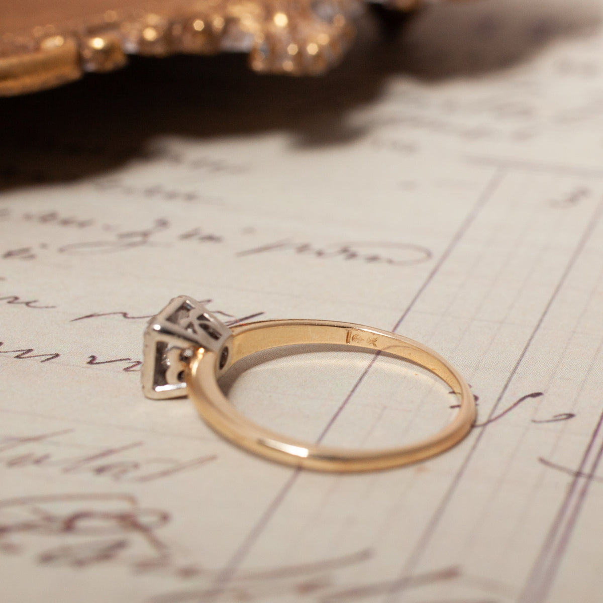 Vintage Mixed Gold Diamond Solitaire Ring, a 14k yellow gold ring with a square-set diamond solitaire on script paper.
