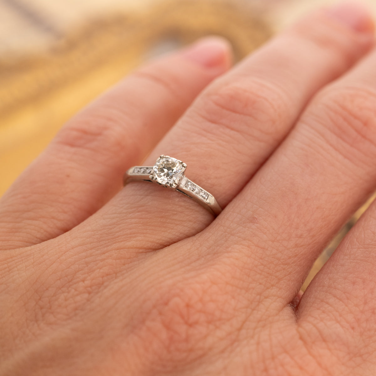 A Vintage Old European & Single Cut Diamonds Ring in 14k white gold, worn on a finger with accent diamonds on the band.