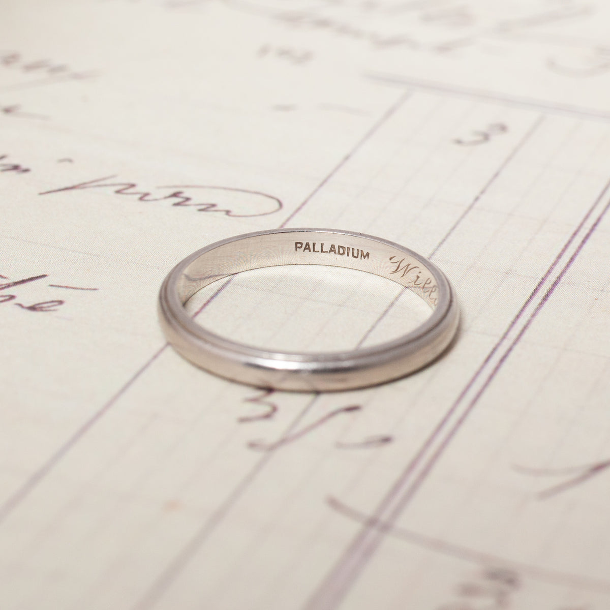 A silver-colored Vintage Palladium Band engraved with the word PALLADIUM on the inner surface.