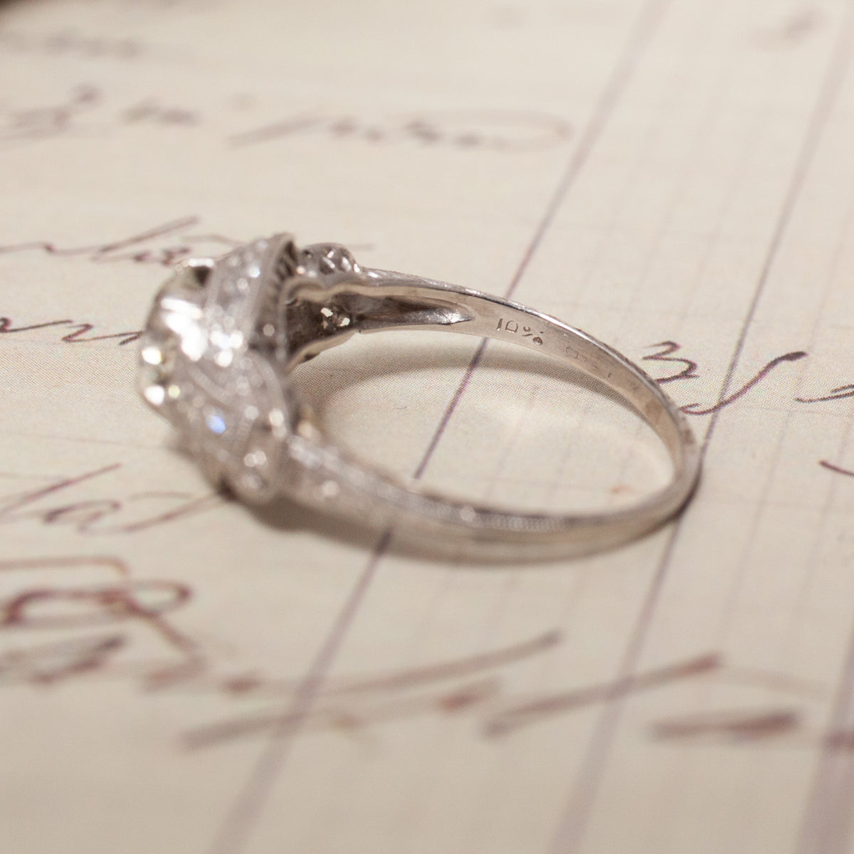 Vintage Transitional Cut Diamond Halo ring on an 18K white gold band, resting on vintage handwritten correspondence.