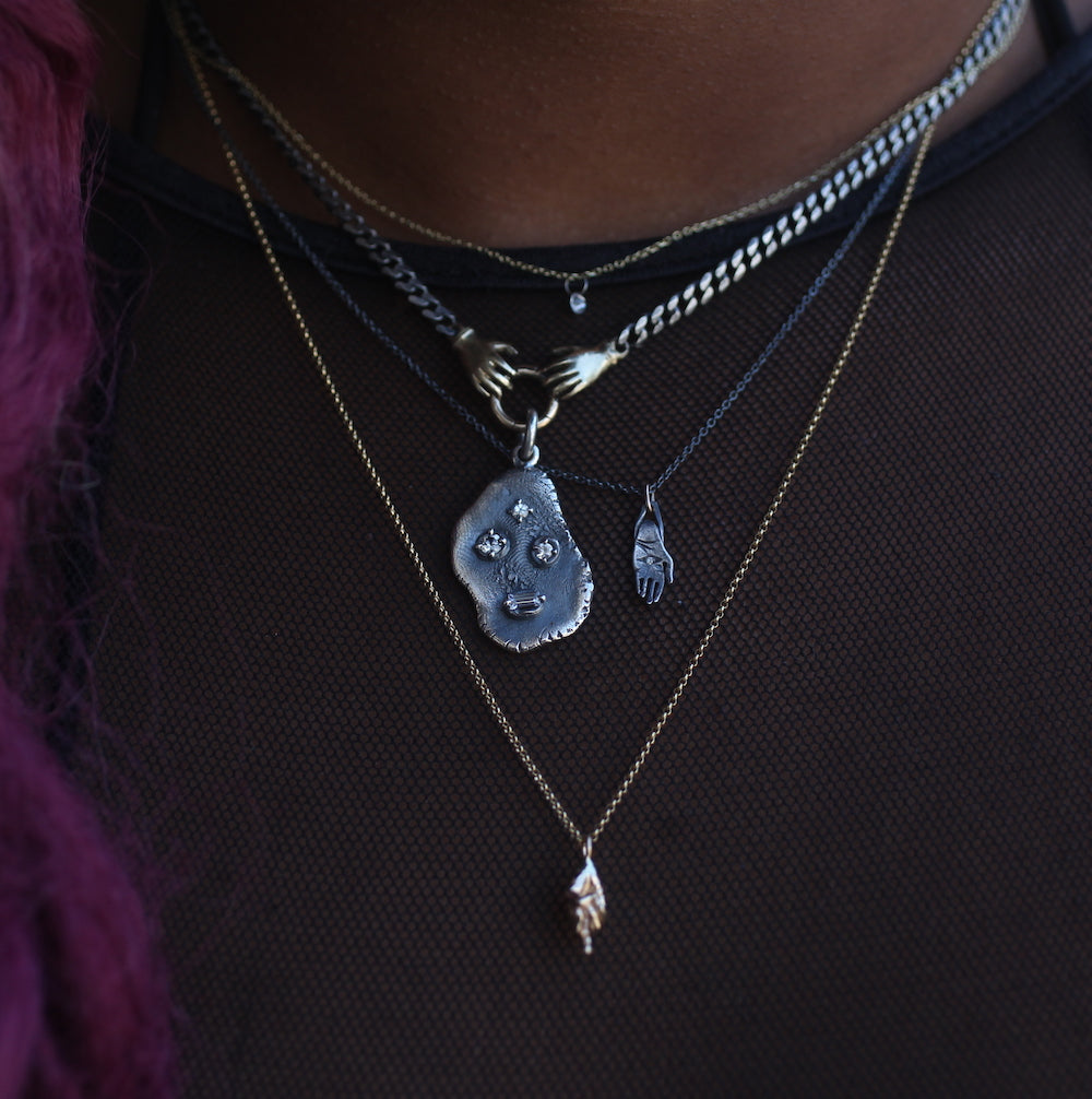 faces pendant by annabelle epstein on a fob grip necklace amidst three chain and pendant necklaces