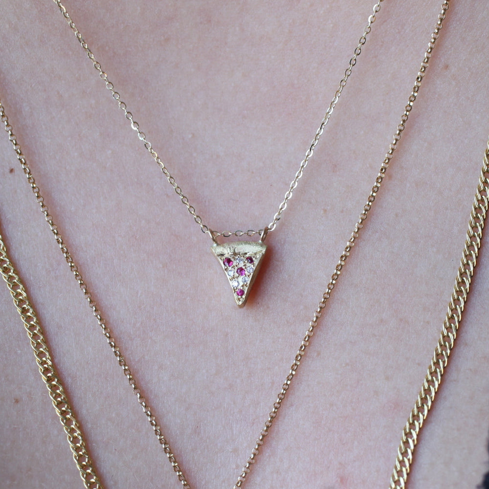 Fiat Lux Pizza Necklace: a close-up of layered 14k gold necklaces featuring a pizza slice pendant with red and clear stones.