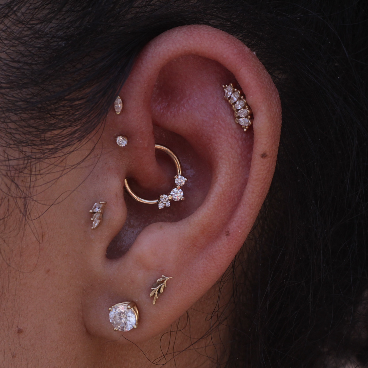 Close-up of an ear adorned with BVLAs 14k gold Ripple Ring piercing jewelry — a stunning, elegant seam ring.