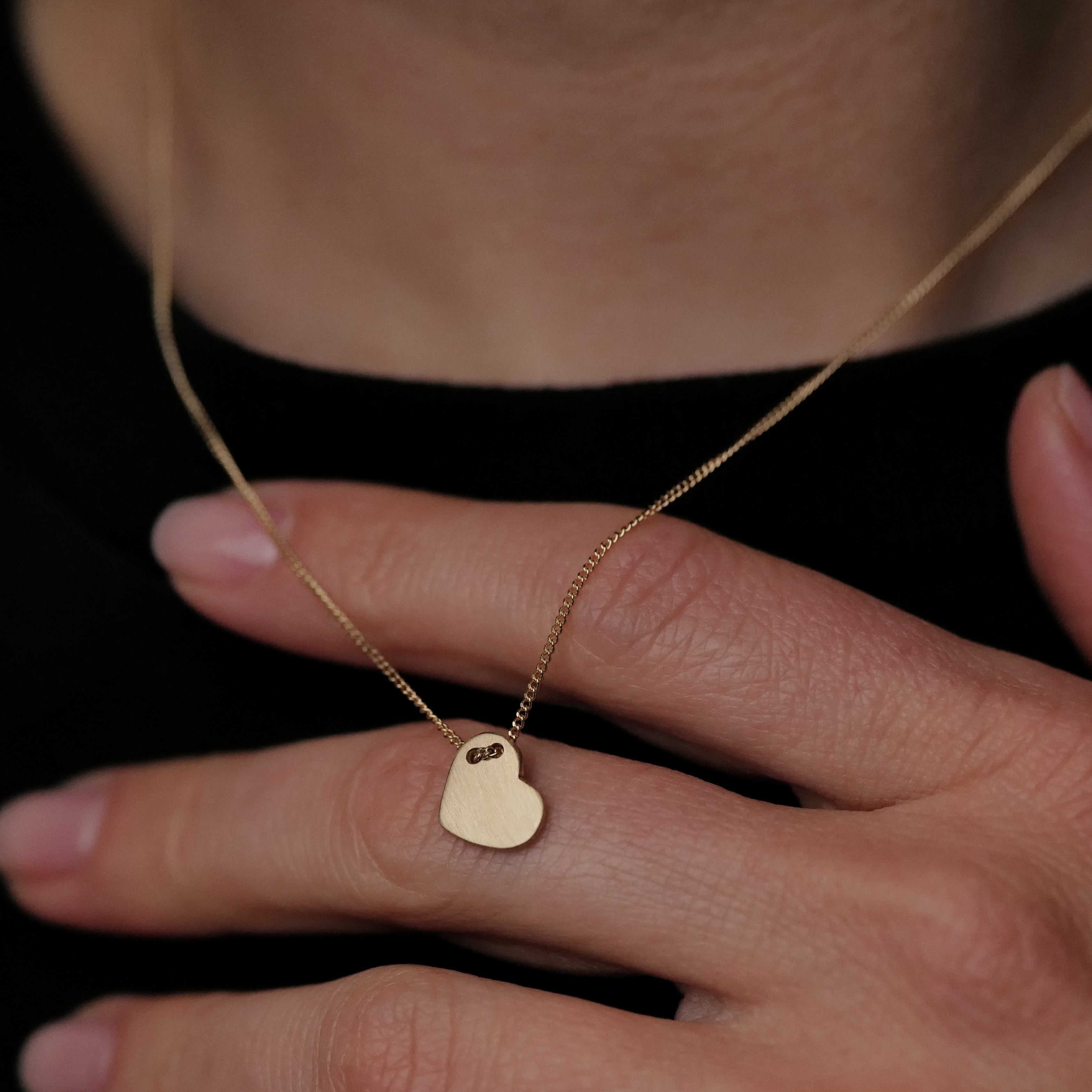 Close-up of a hand with Daisy San Luis BFF Heart Necklace (G)—your perfect 14K gold everyday friendship jewelry.