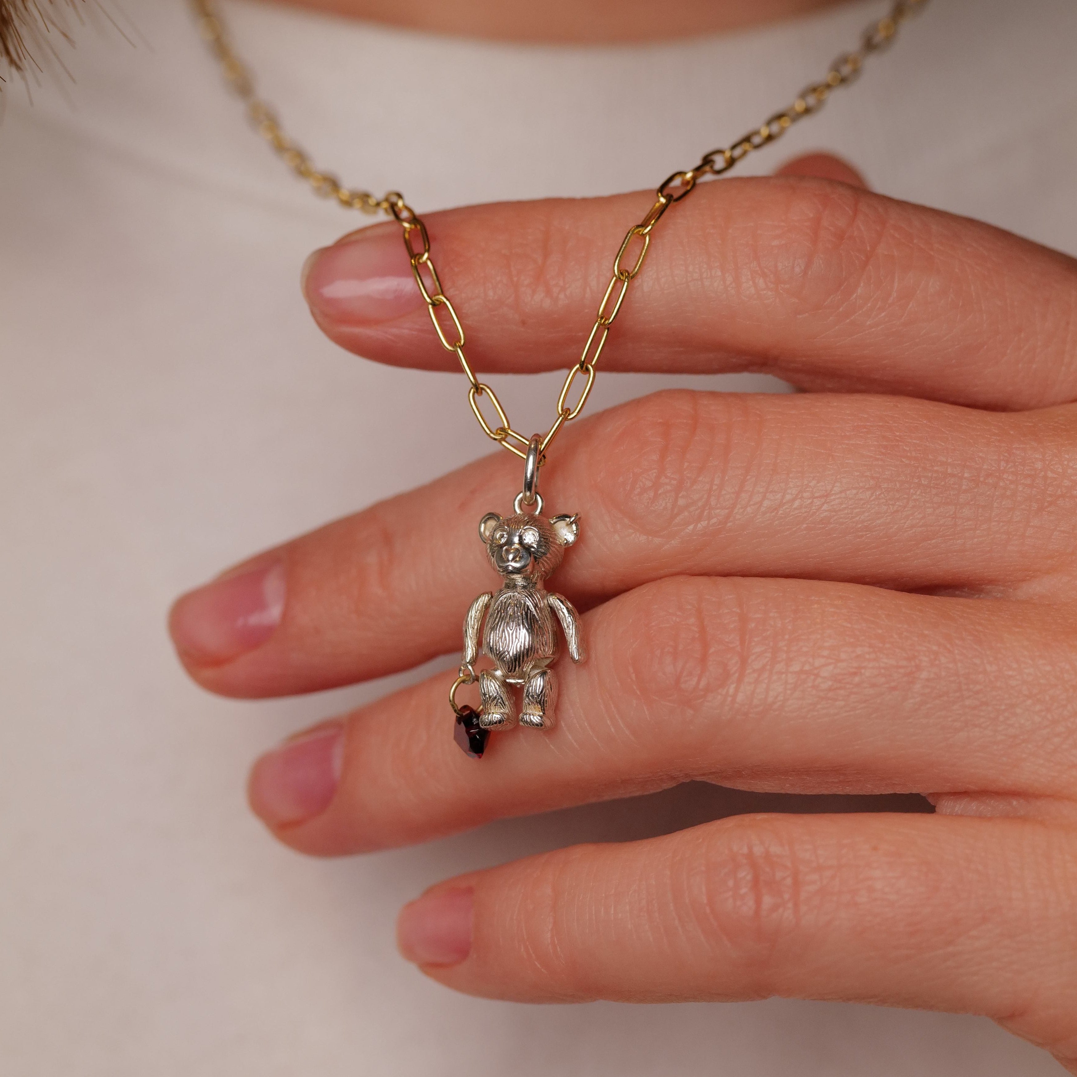 Hand holding Fiat Luxs Mr Teddy Charm (S) gold chain necklace with sterling silver teddy bear pendant.