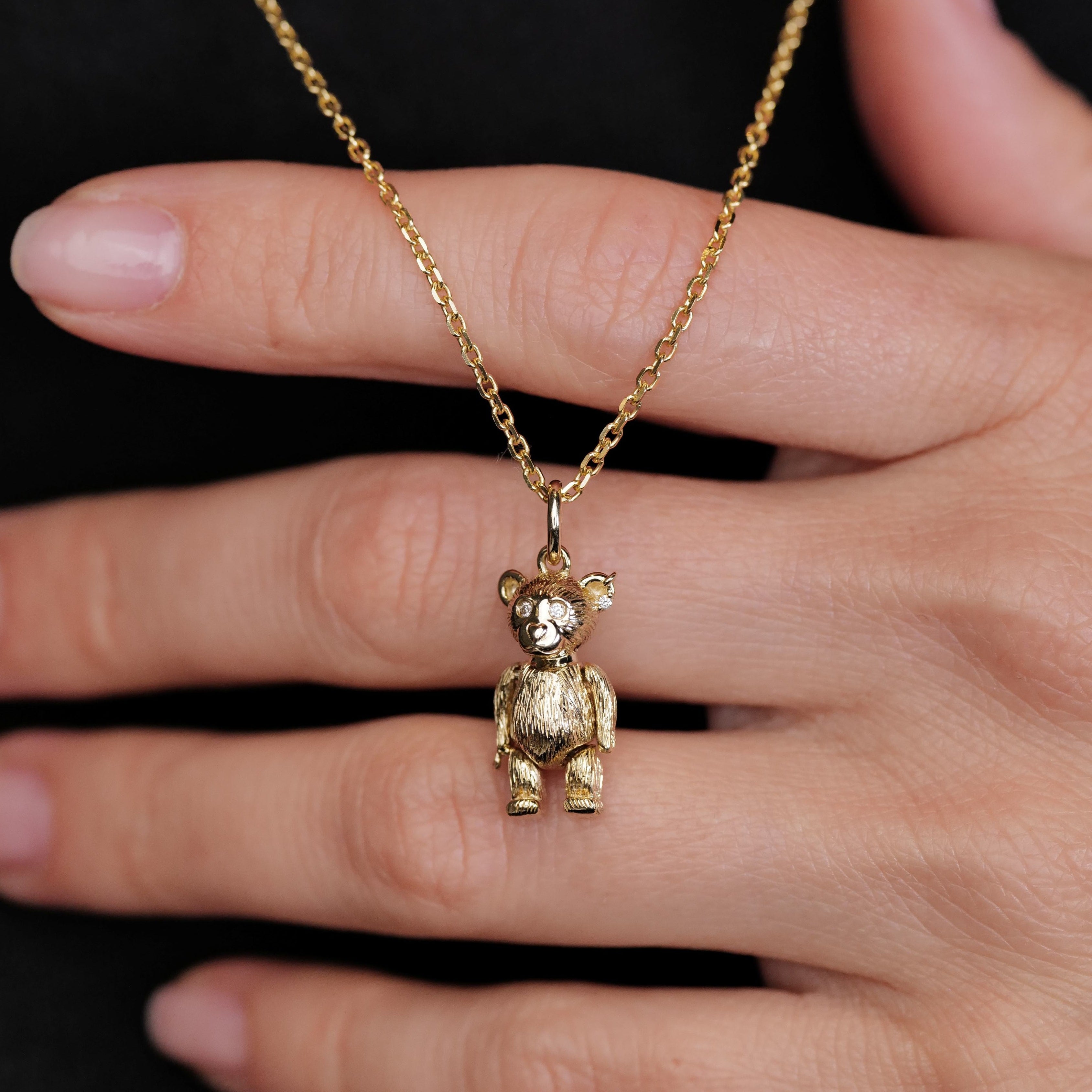 Fiat Lux Mr Teddy Charm (G): vintage-inspired 10K gold bear pendant necklace, shown on a hand with black backdrop.